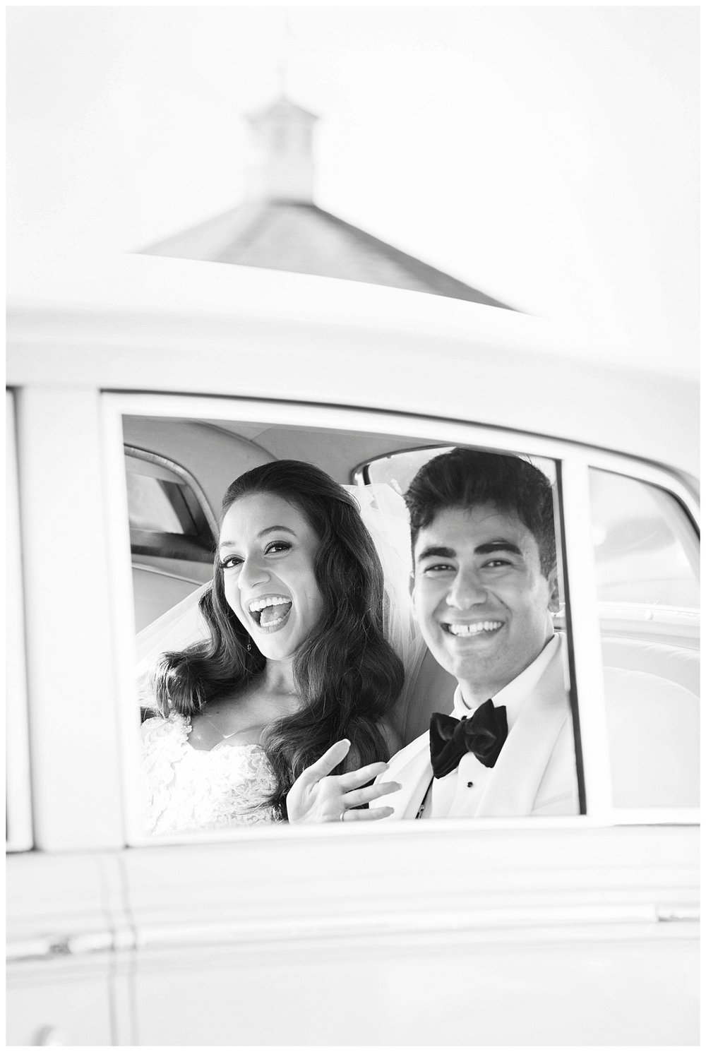 bride and groom smiling sitting inside white Rolls Royce