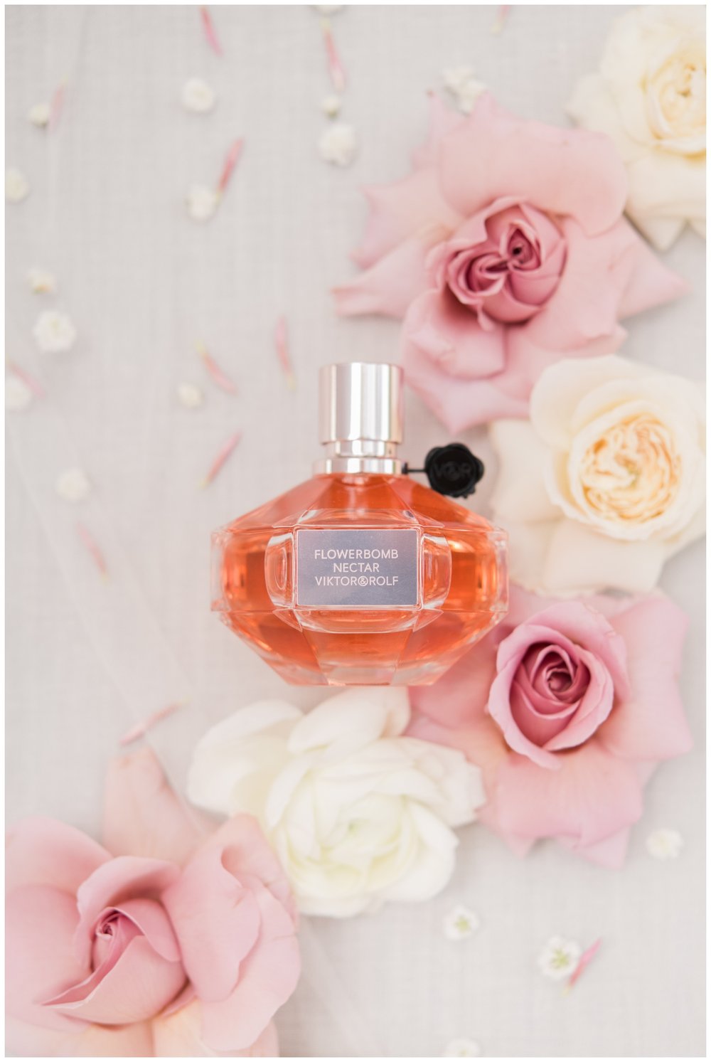 perfume bottle surrounded by white and blush florals