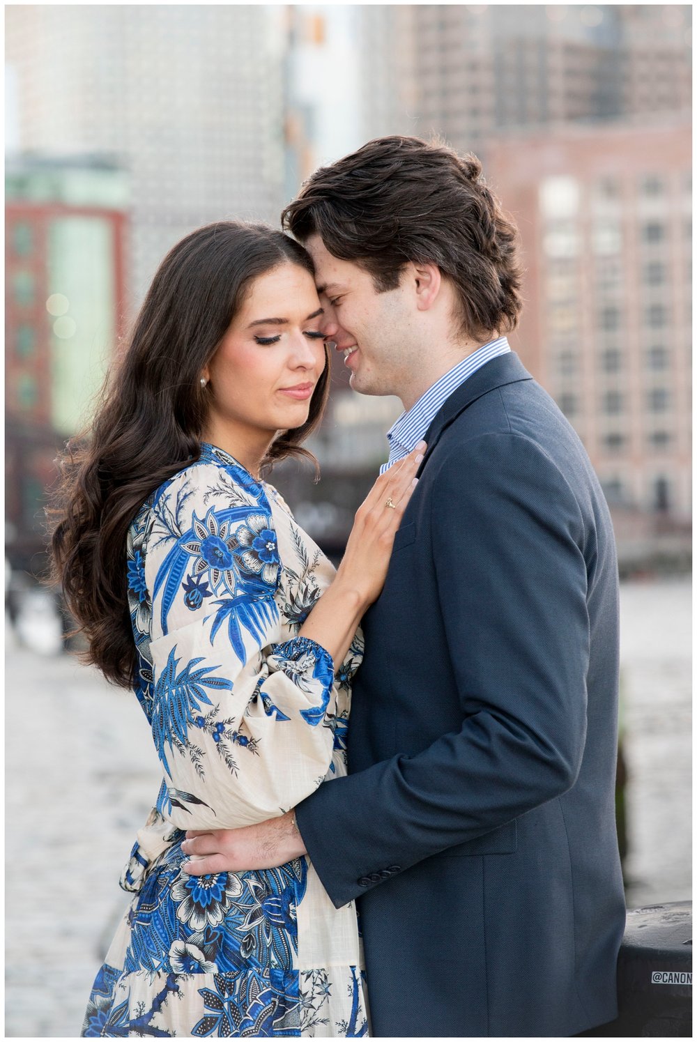 nuzzling pose of engaged couple in navy and cream formal attire