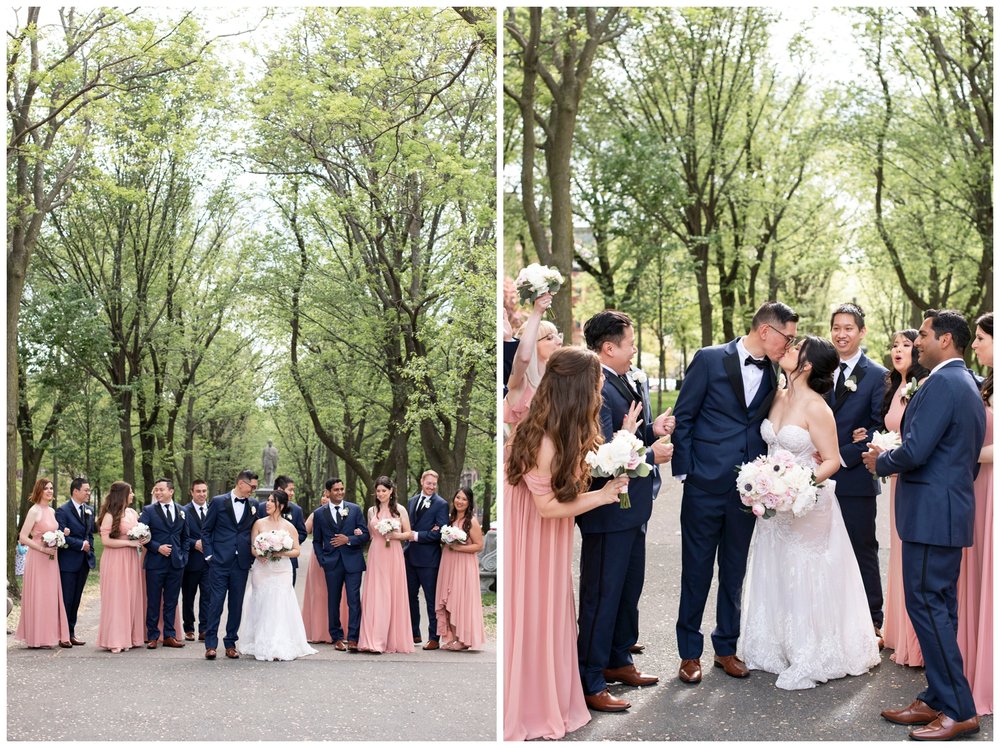 bride and groom kissing surrounded by full bridal party outdoors Boston