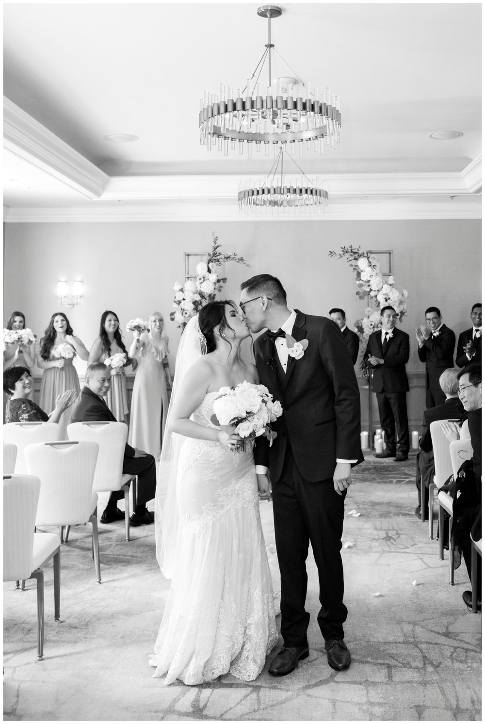 black and white image of bride and groom kissing after indoor wedding ceremony