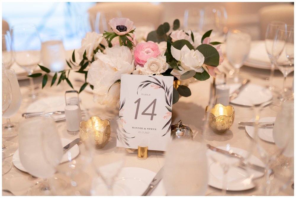 detail image of white and pink table number at wedding reception