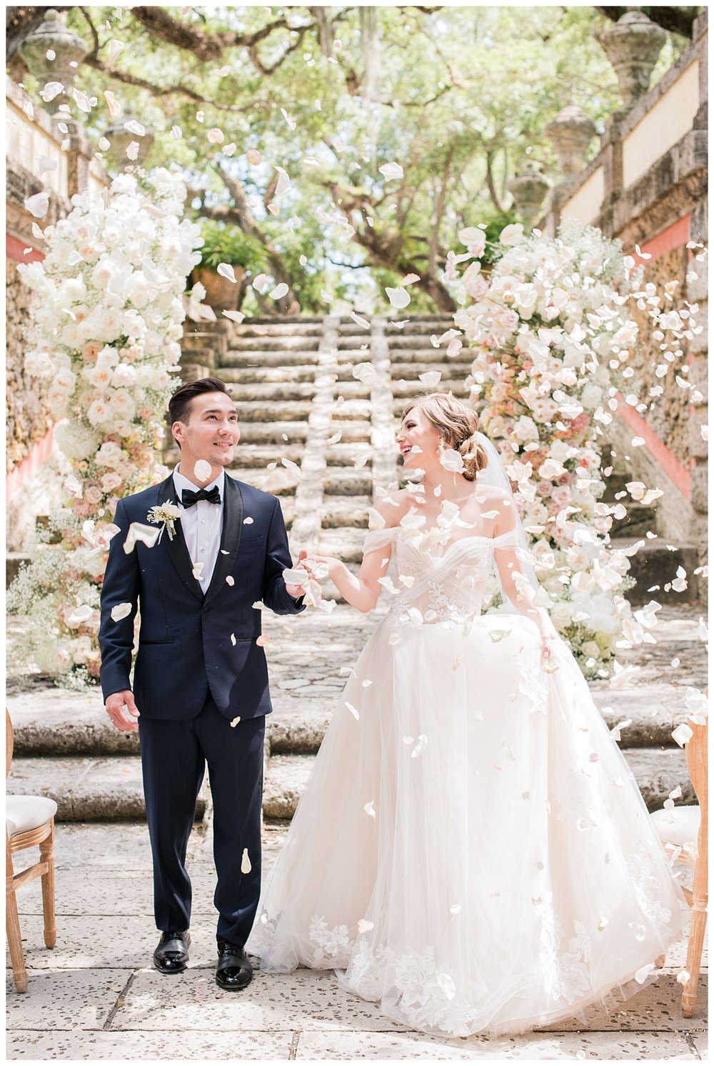 bride and groom exiting outdoor wedding ceremony under rose petals