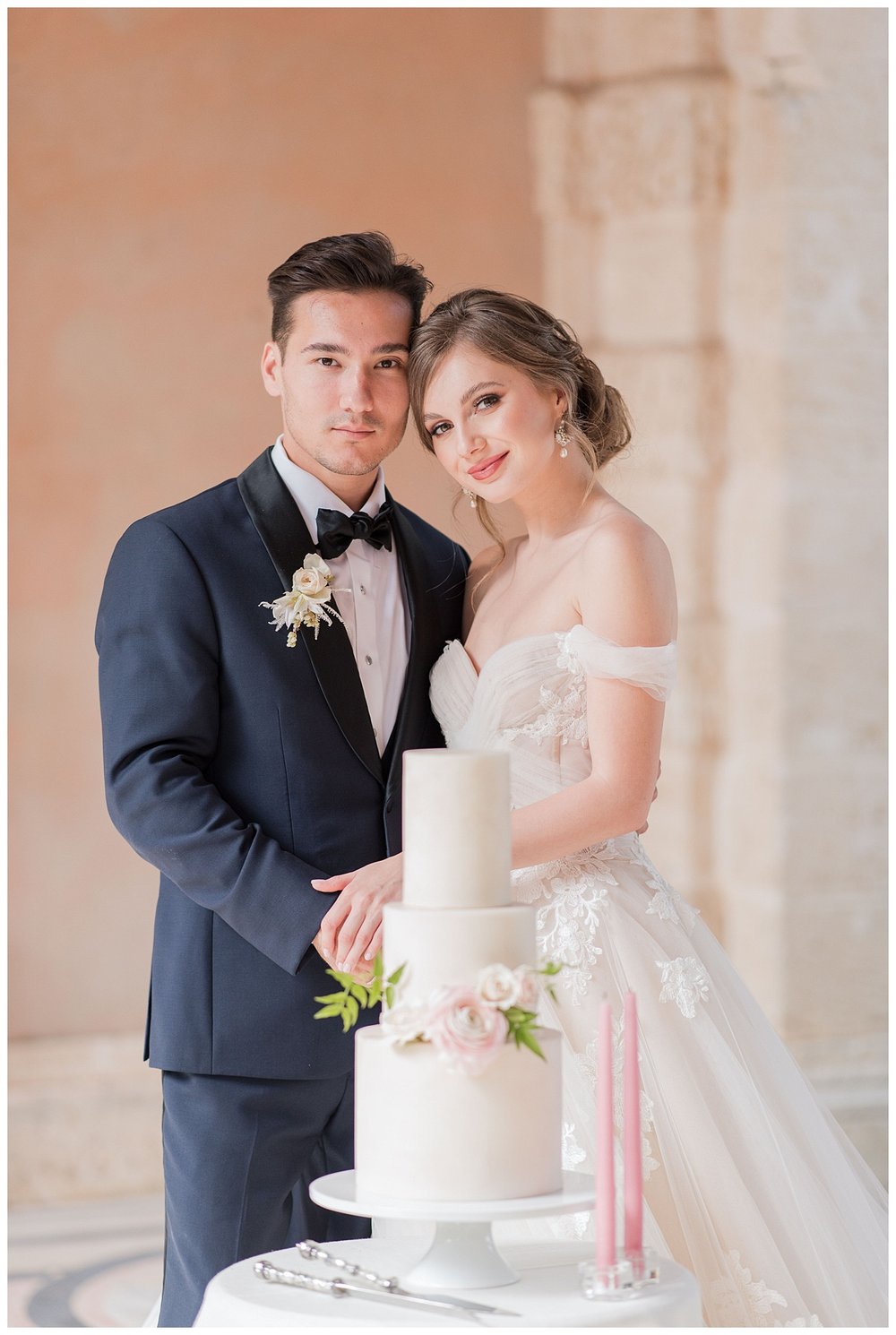 bride and groom side by side behind three tier wedding cake