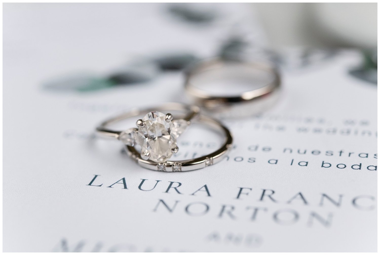 wedding rings sitting on top of white invitation suite