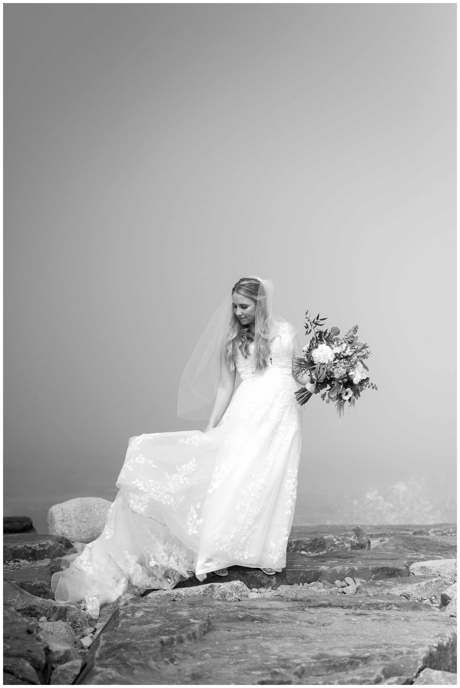 bride standing on rocks swaying dress for New England wedding photographer