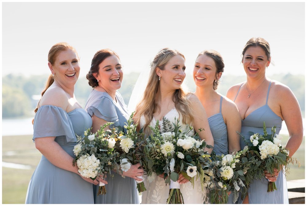 bride with bridesmaids in dusty blue dresses laughing