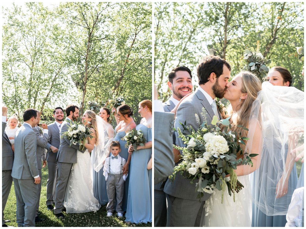 bride and groom kissing with wedding party cheering for New England wedding photographer
