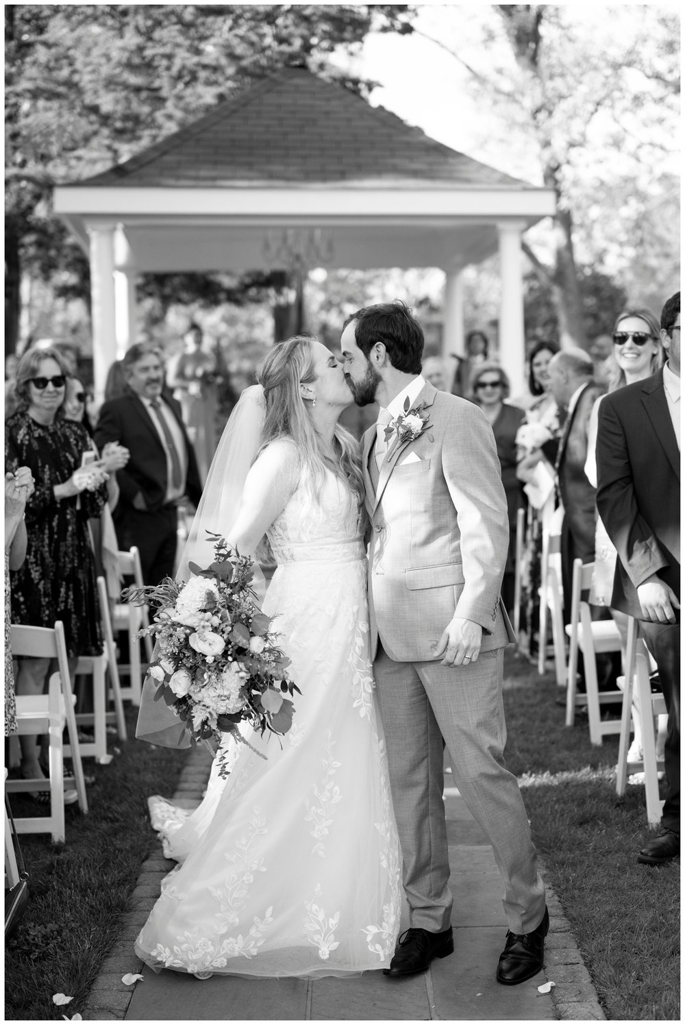 black and white image of bride and groom kissing wedding ceremony