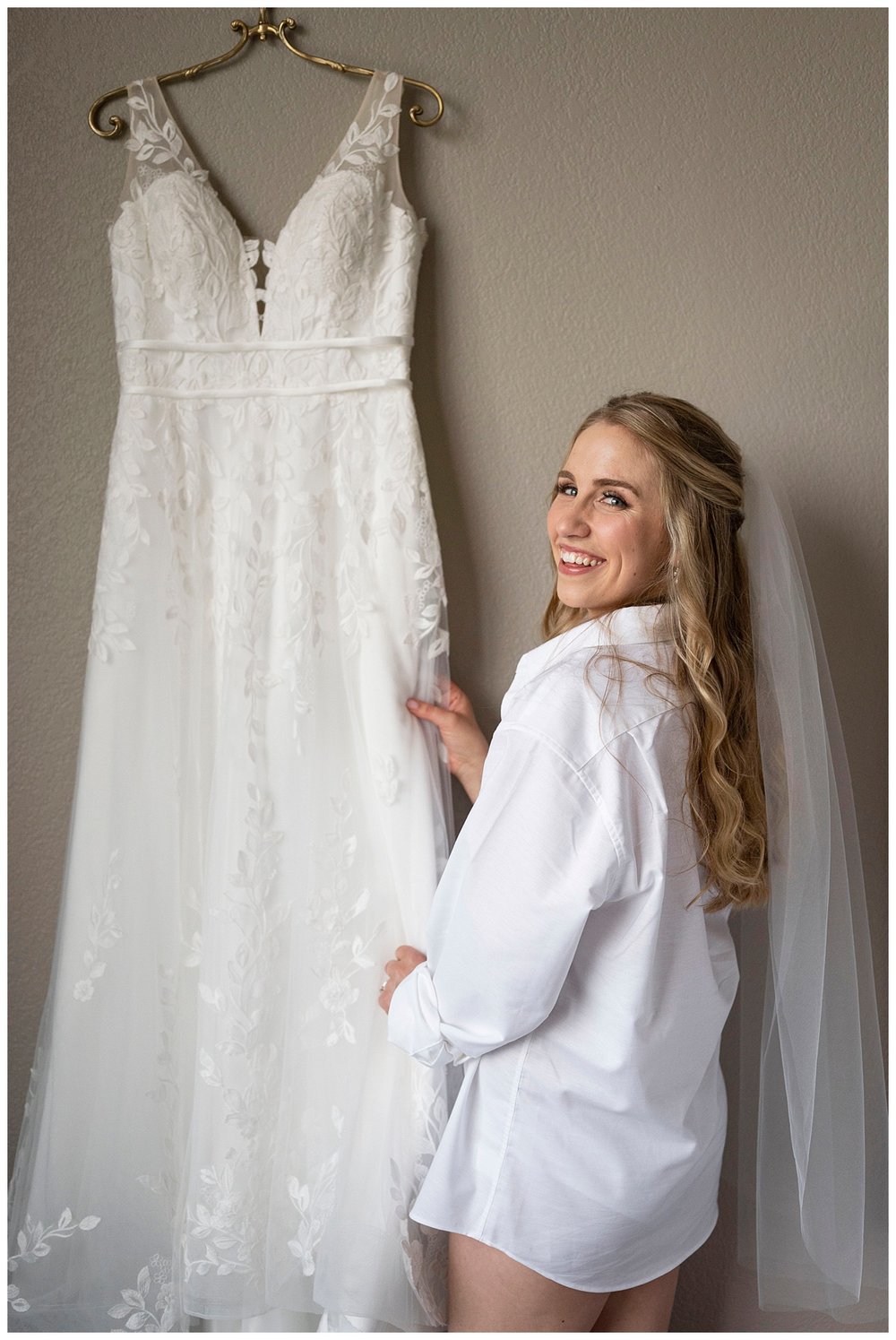bride getting ready with earrings and holding wedding gown