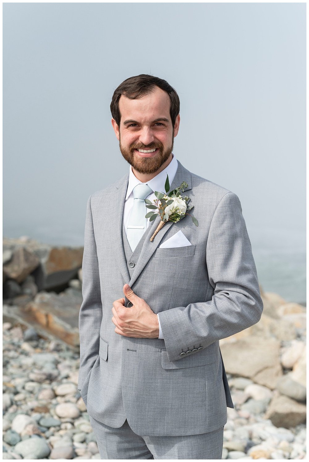 groom in gray suit smiling at camera for New England wedding photographer