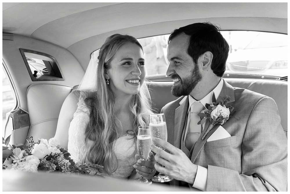 bride and groom inside getaway car toasting champagne in New England, Massachusetts