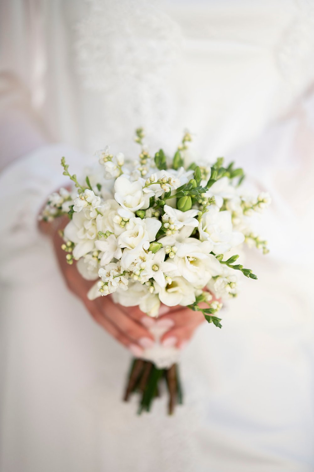 bride holding all white wedding flowers