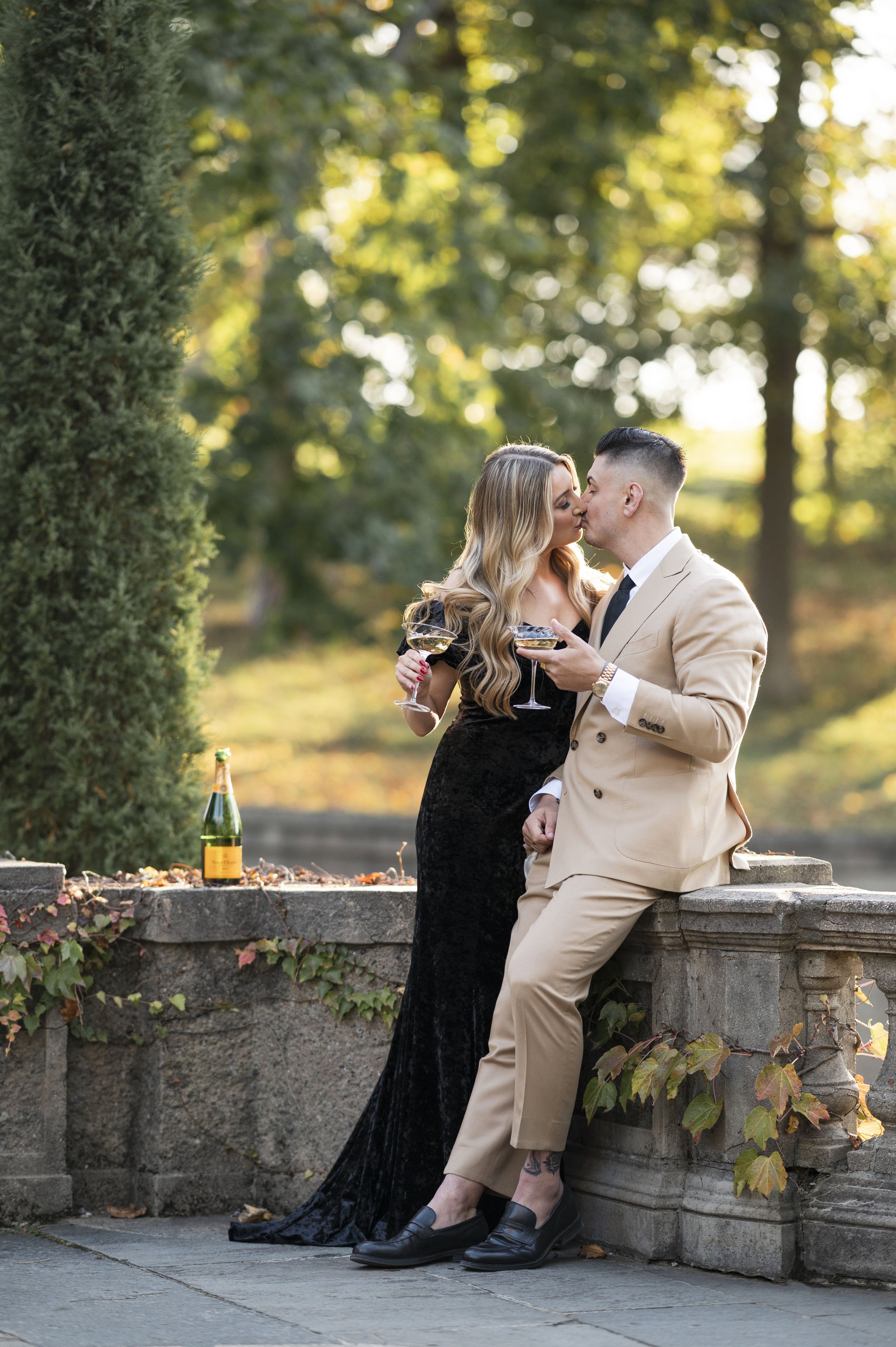 couple posing during outdoor engagement session with champagne