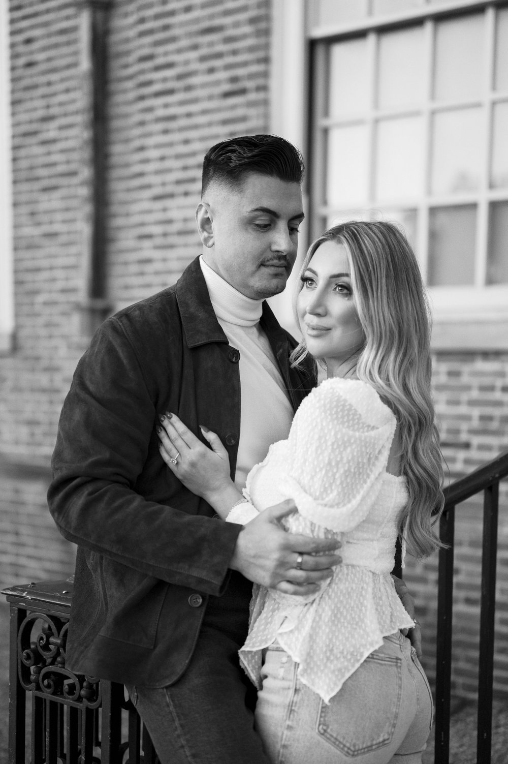 couple standing in front of brick building posing for engagement photos