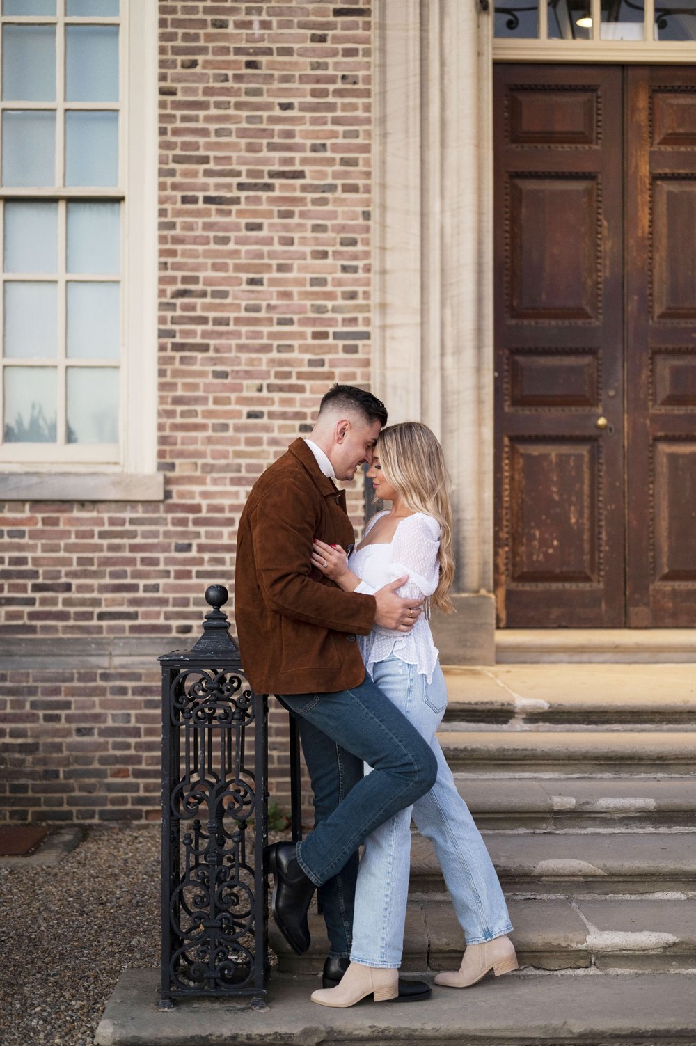 couple standing in front of brick building posing for engagement photos