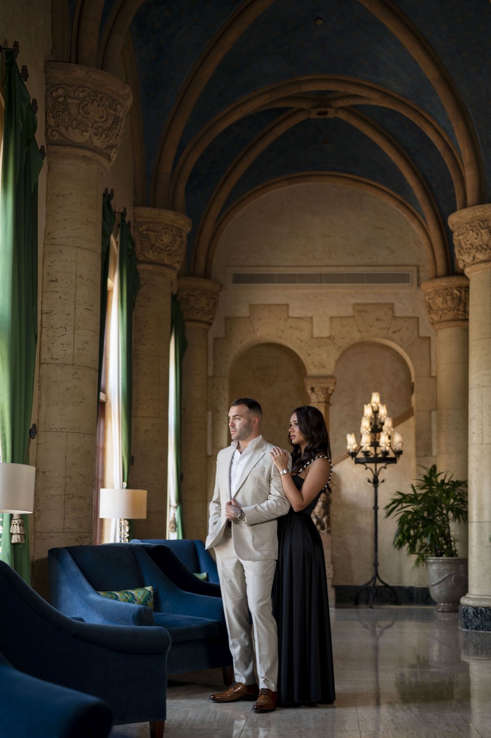 guy and girl standing inside of the Biltmore hotel Miami lobby as they look outside the window