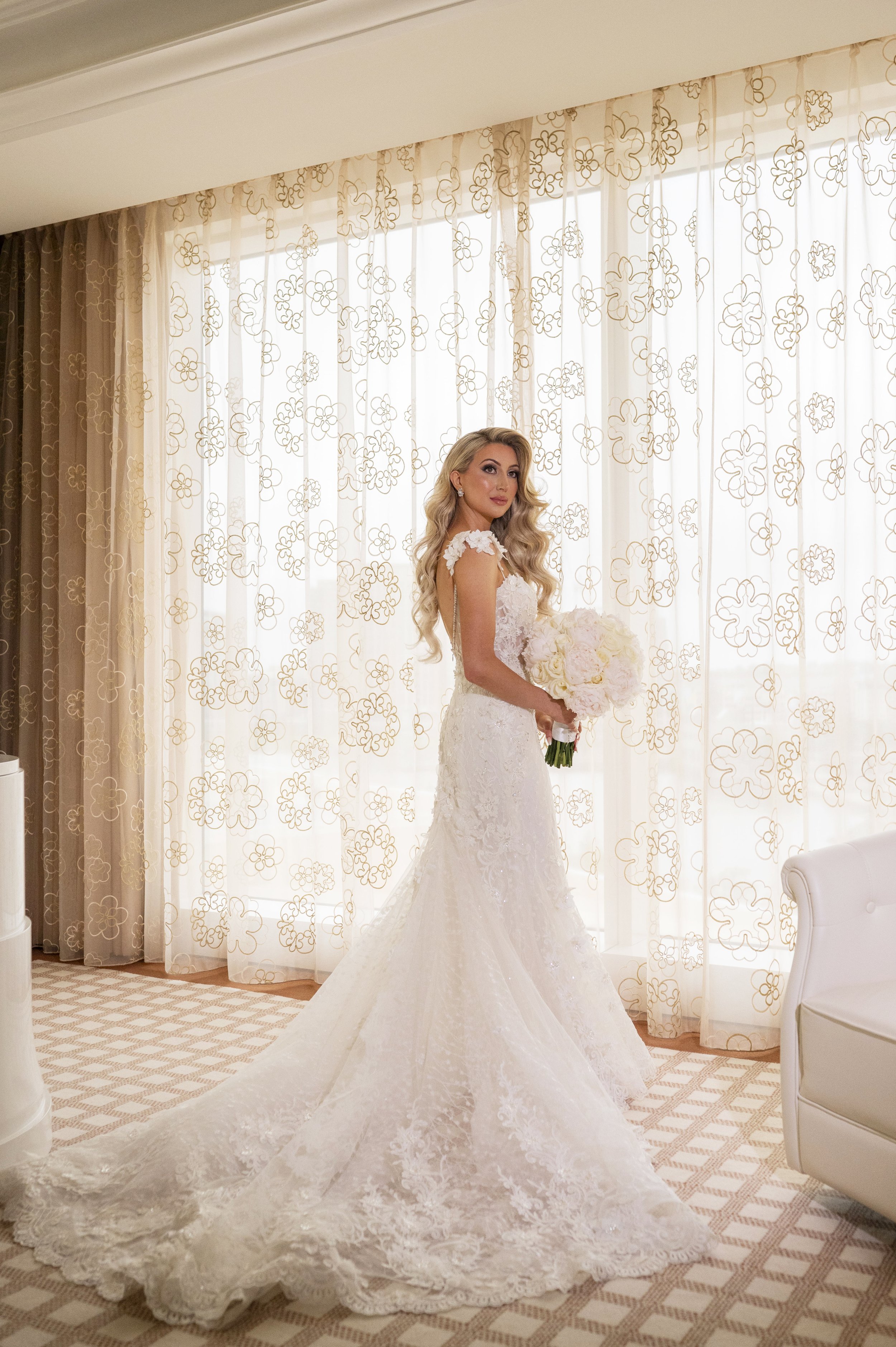 bride wearing gown holding bouquet posing in her bridal suite