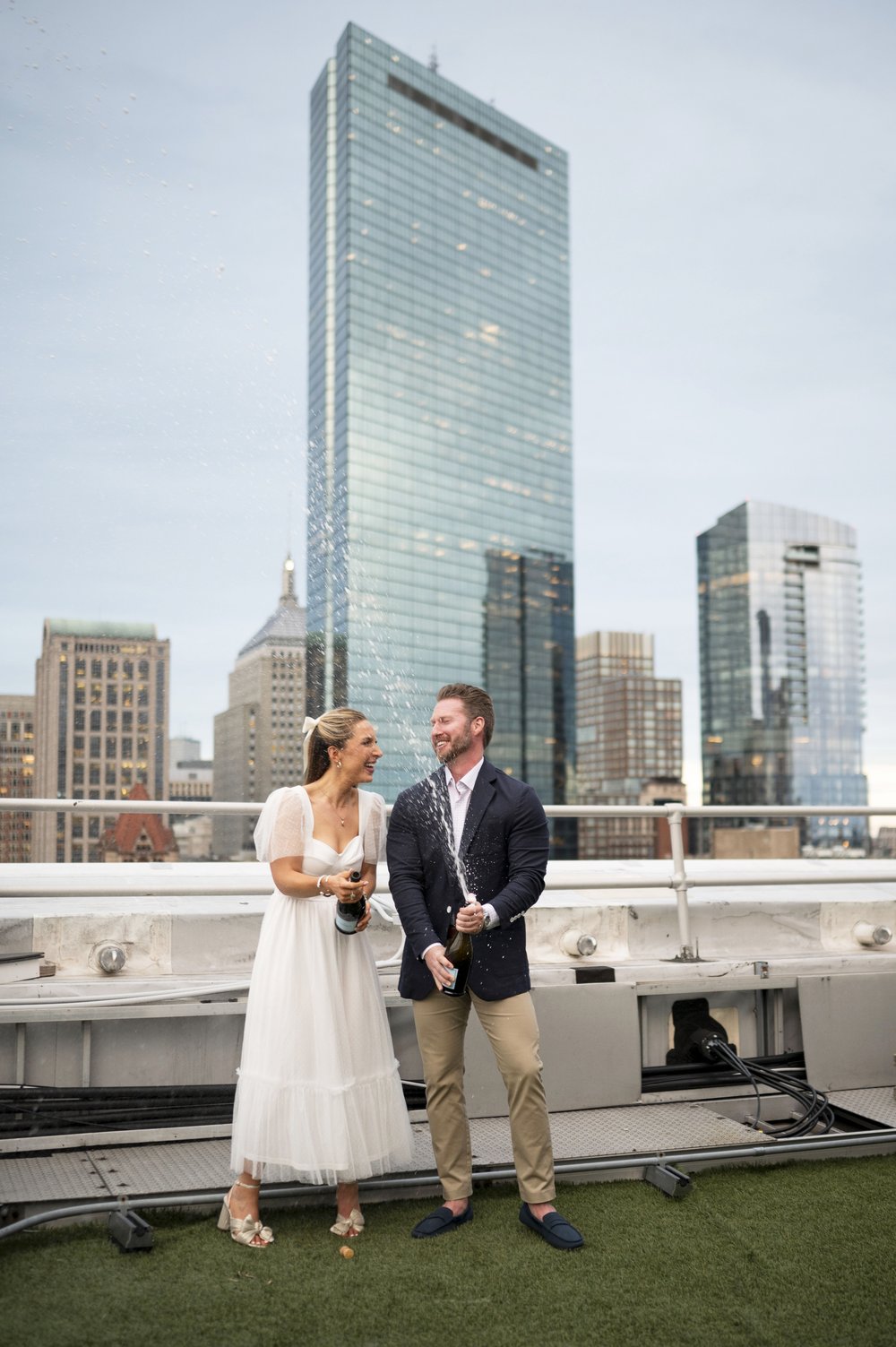 bride and groom opening champagne Rooftop Engagement Photos