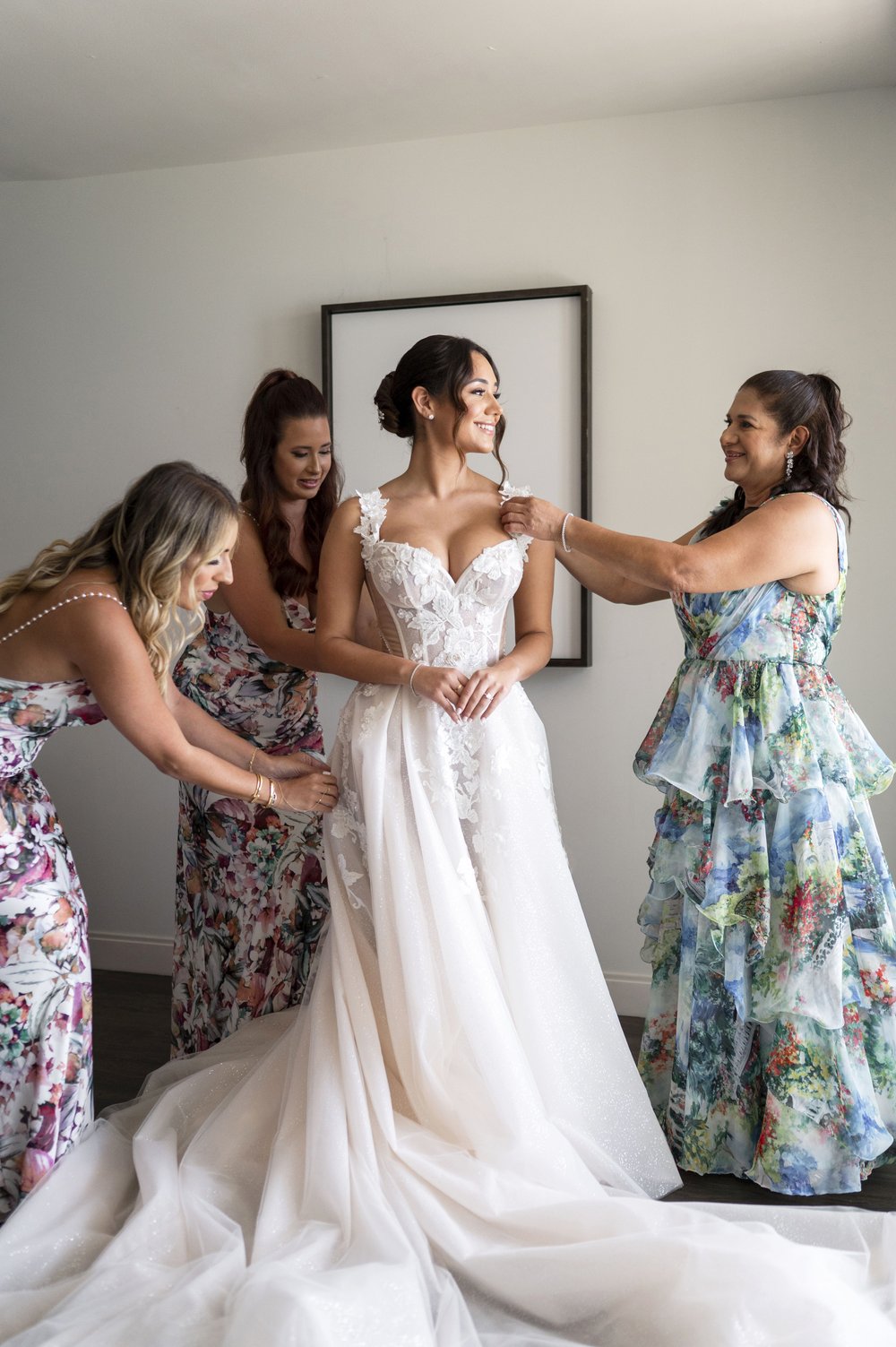 bridesmaids helping bride putting on her dress
