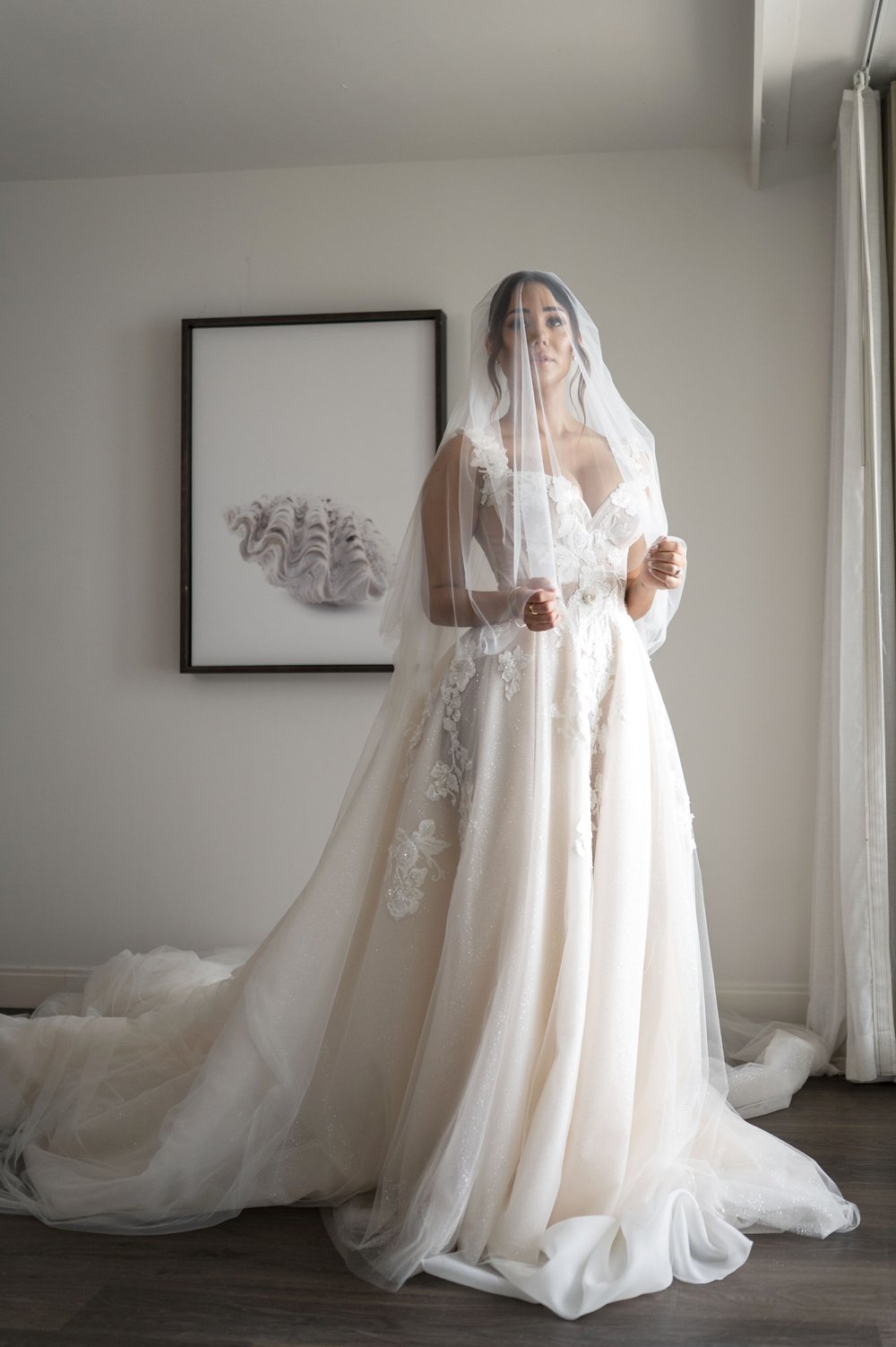 bride posing wearin her veil over her head in her bridal suit