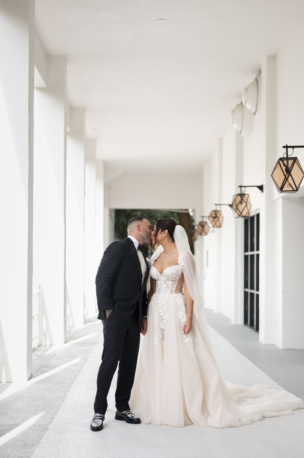 bride and groom kissing in a white corridor area of the bakers cay resort