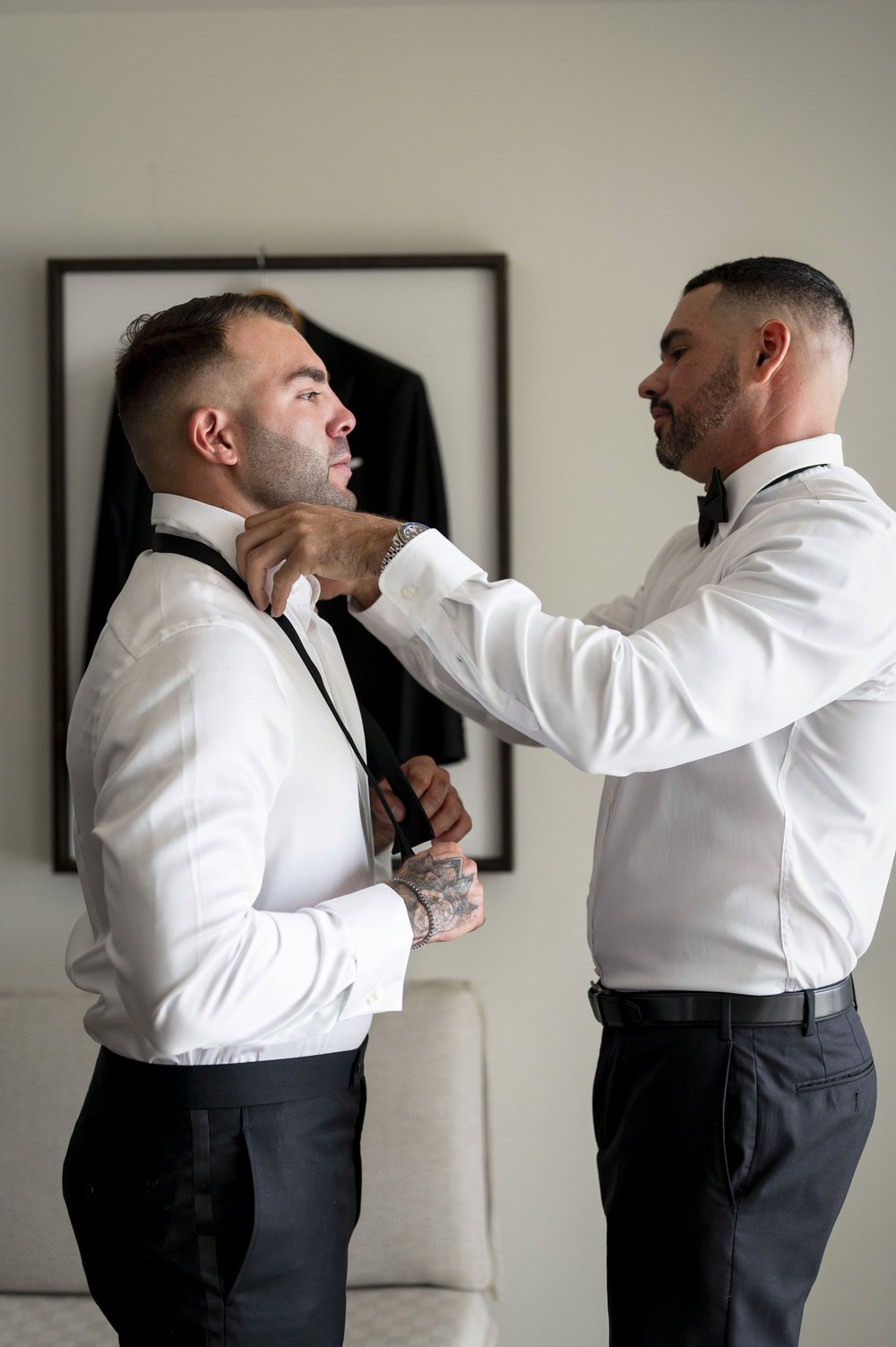 best men puts tie on grooms 