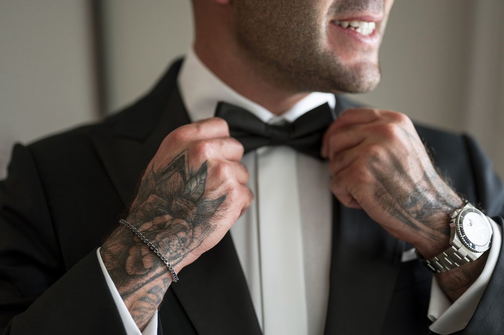 close up of grooms hands as he adjust his bow tie
