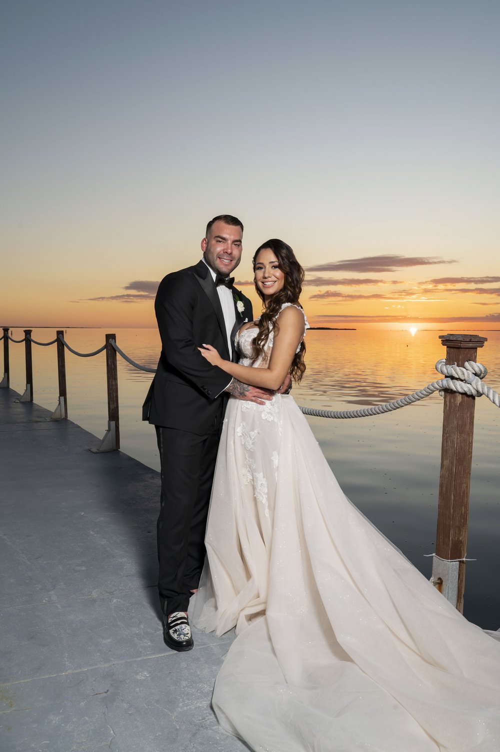 bride and groom posing in a dock during sunset