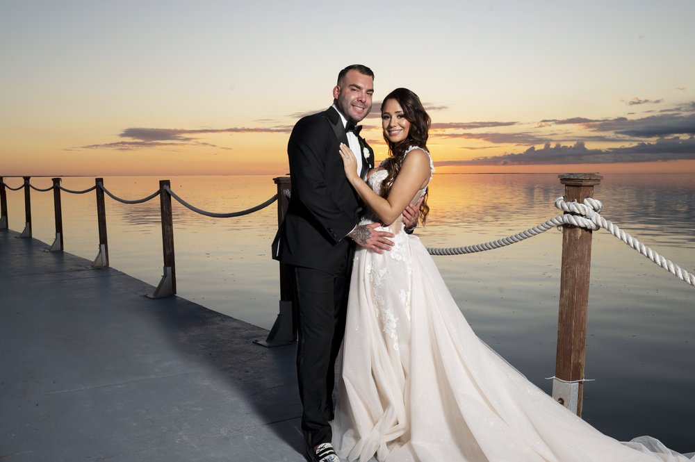 bride and groom kissing in a dock by the water during sunset time