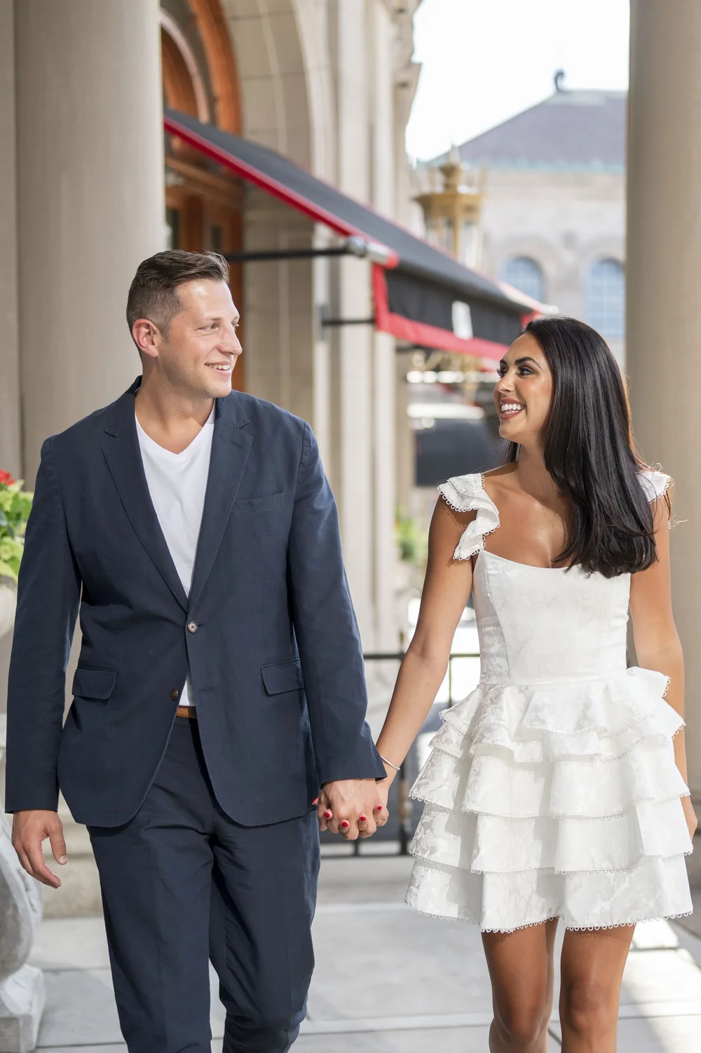 guy and girl looking at each other as they hold hands walking