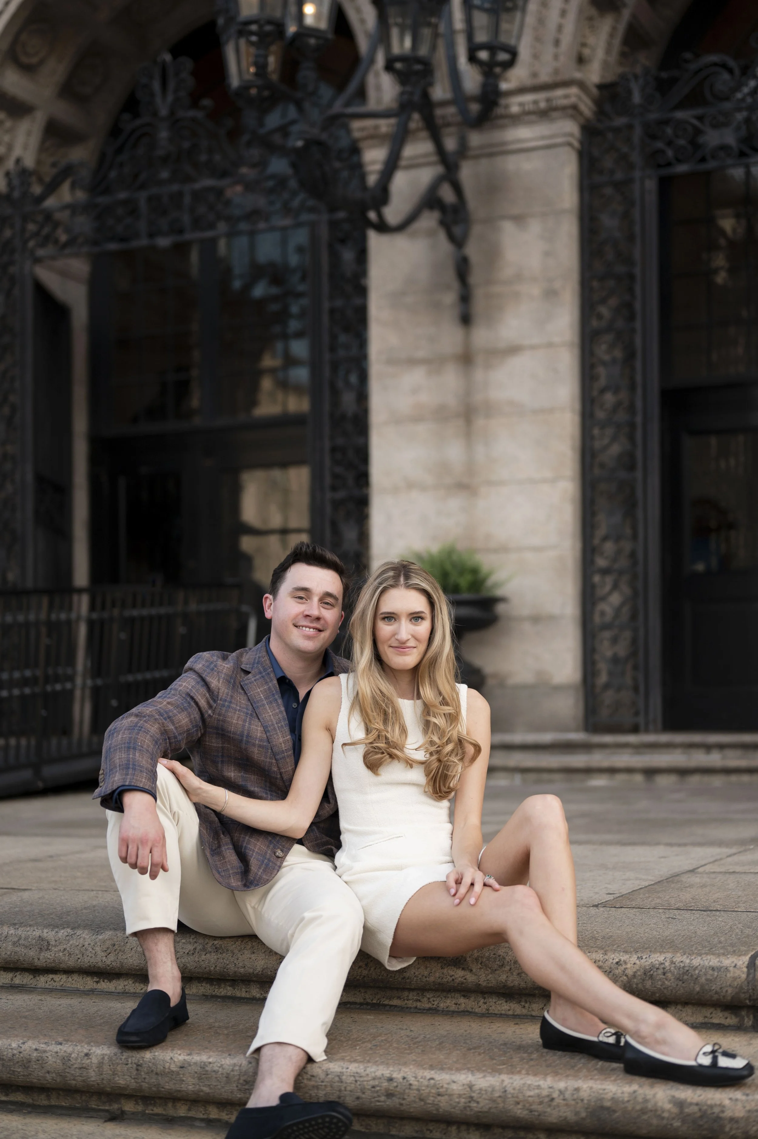 Cathryn and Brendan sitting on the steps of the Boston Public Library during their engagement session