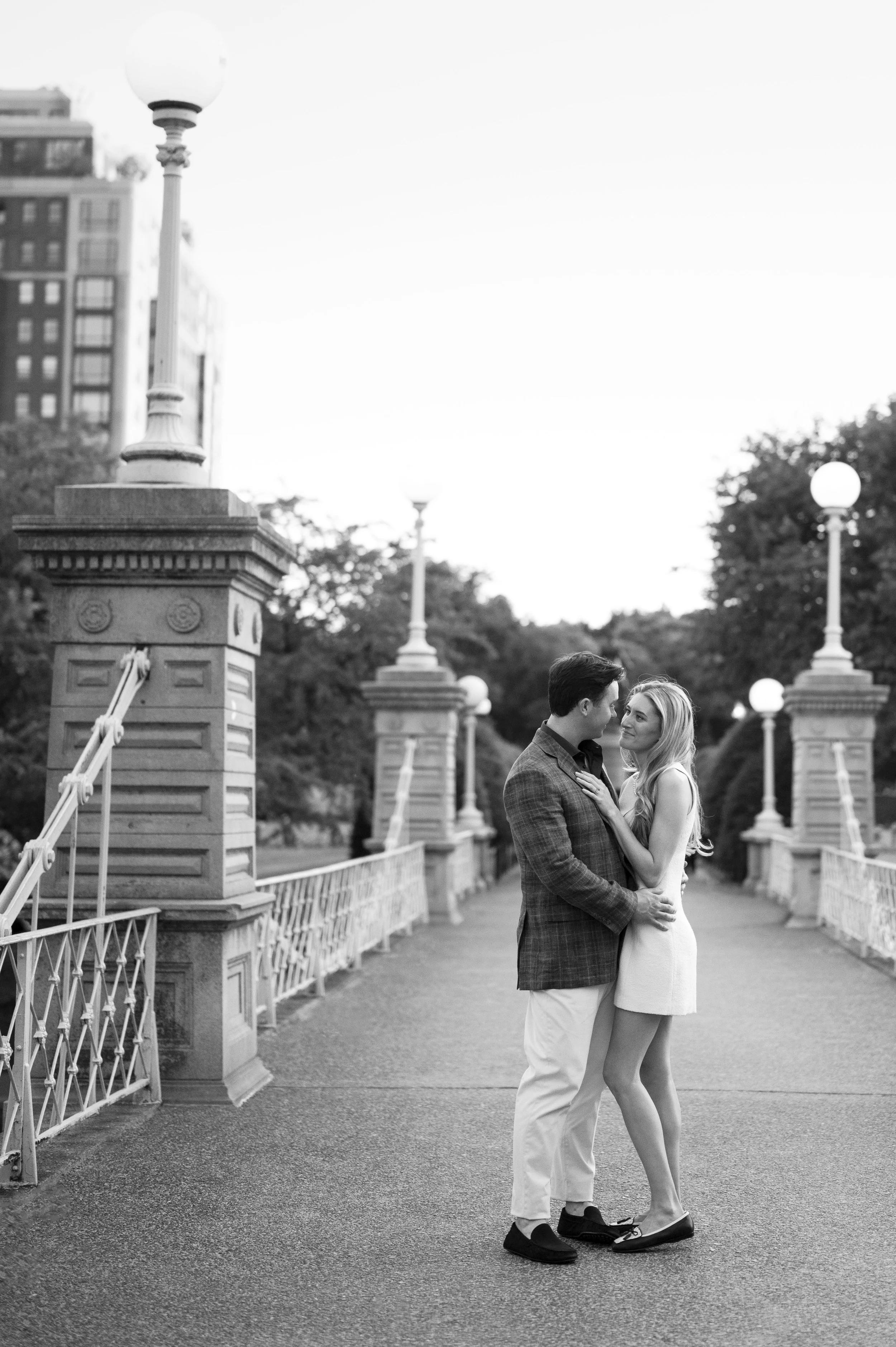 Cathryn and Brendan Standing looking at each other in the middle of the public garden bridge during their engagement session 