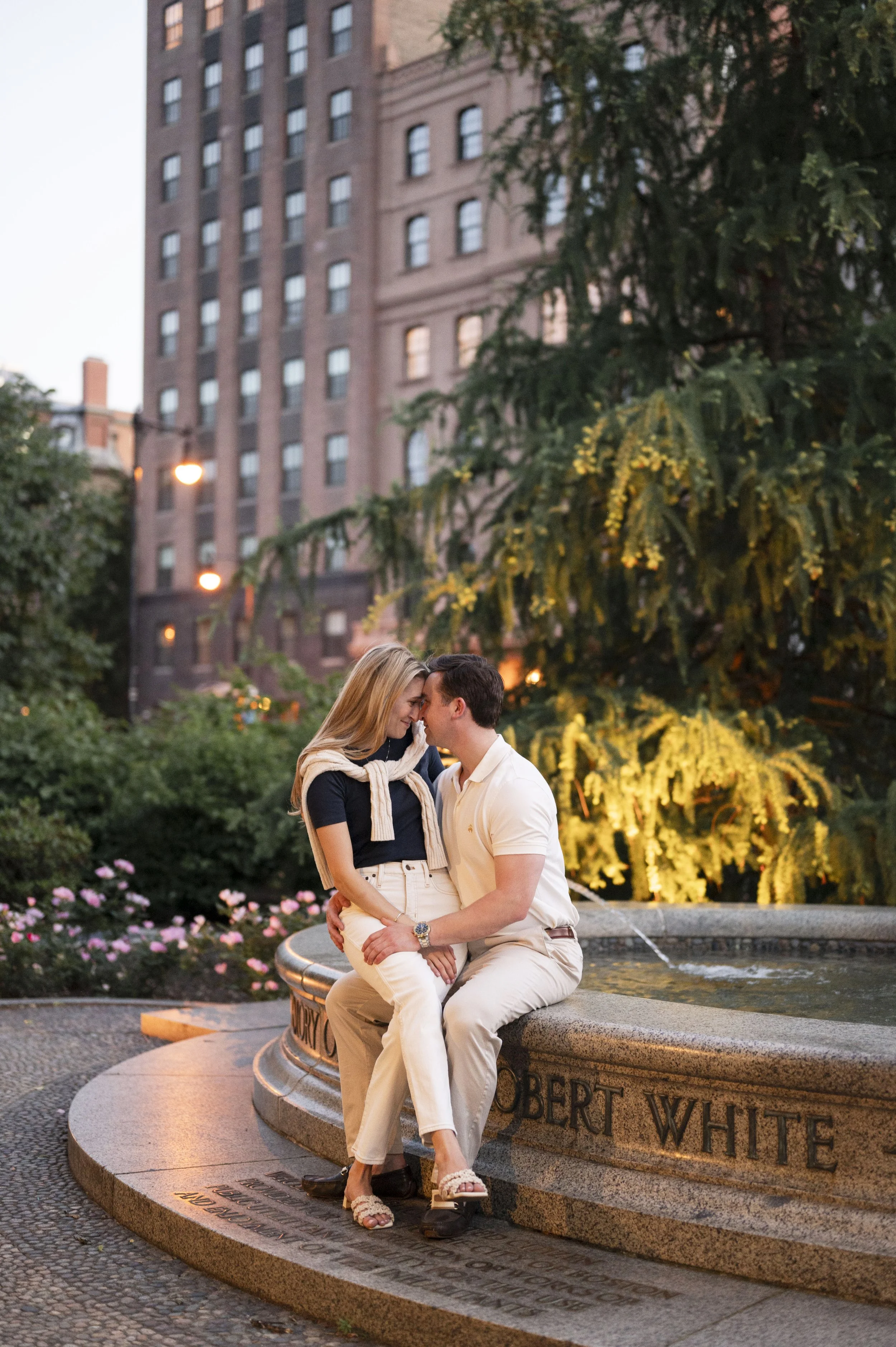 Cathryn and Brendan sitting by the fountain at the public garden during their engagement sesison
