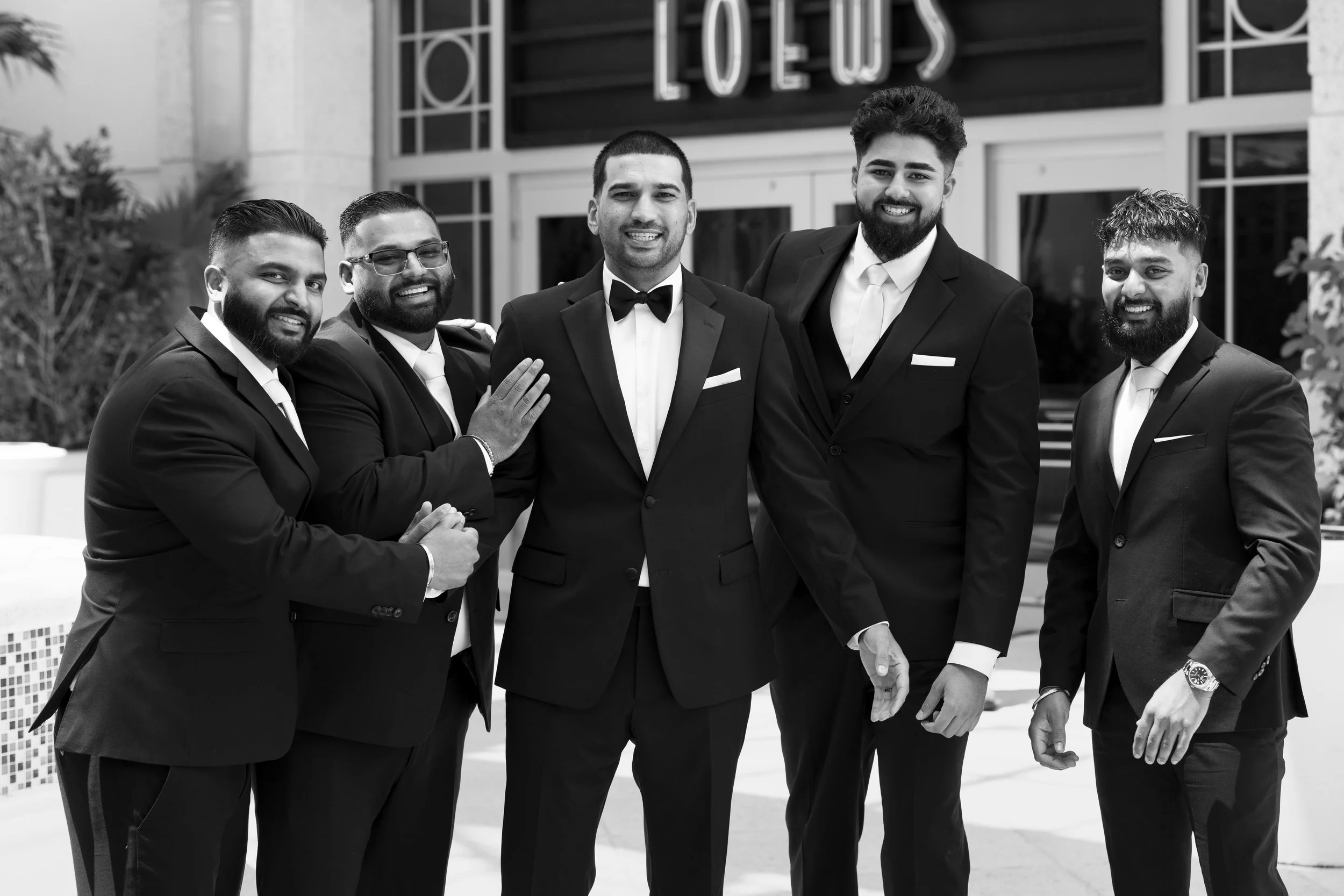 groom and groomsmen posing laughing in front of the Loews hotel miami beach