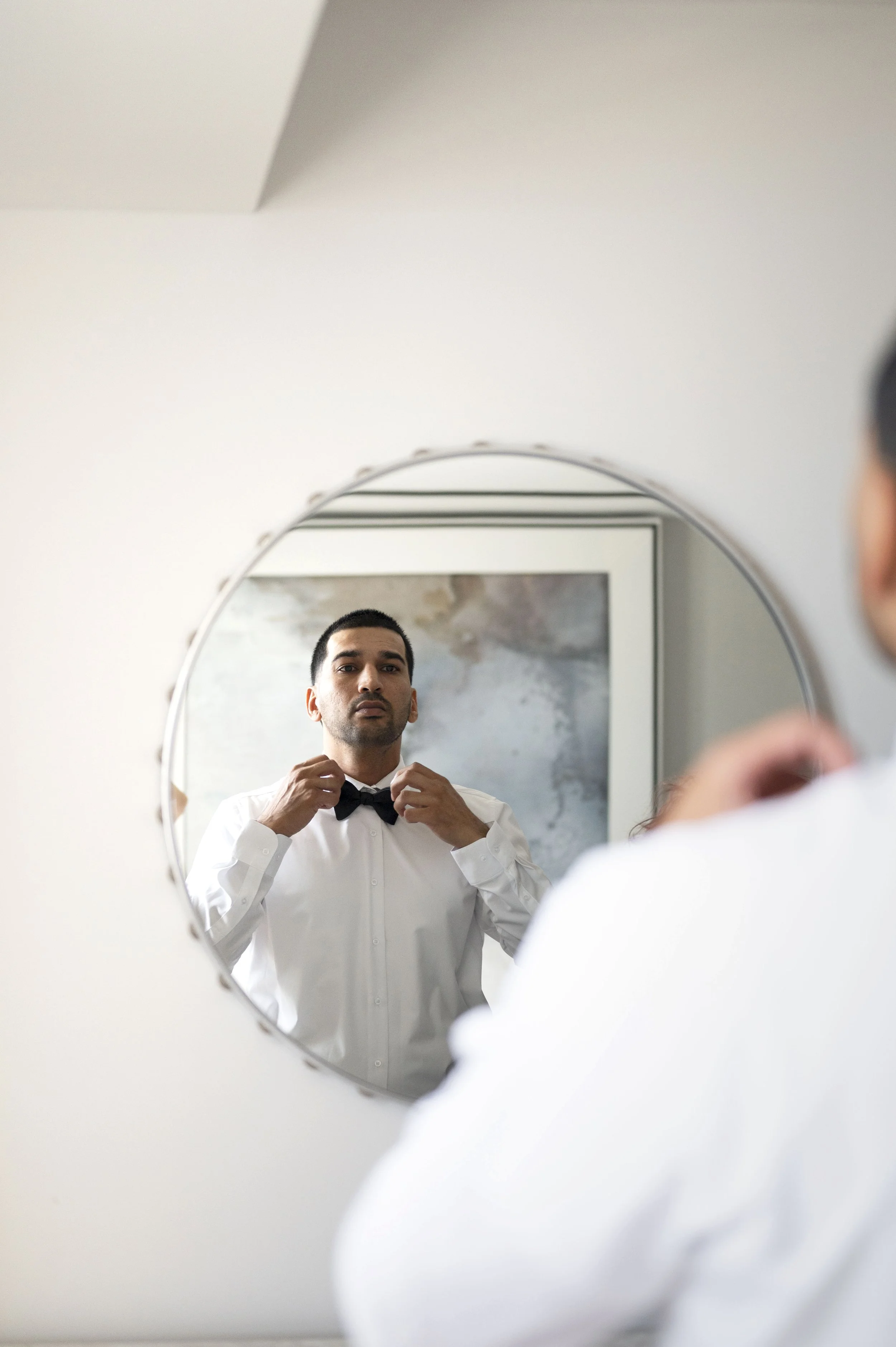groom looks himself at a mirror in the getting ready suite at Loews hotel miami beach
