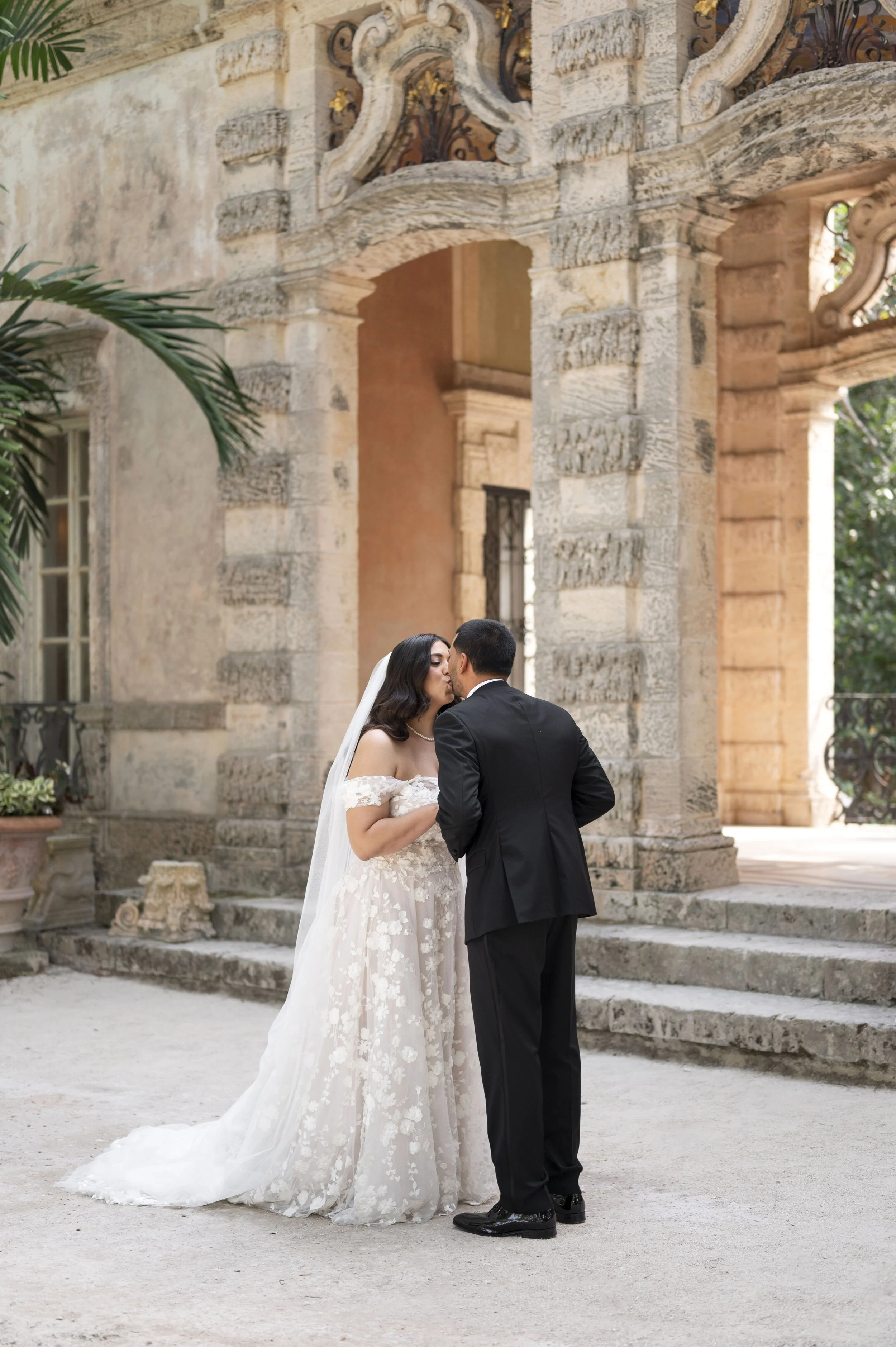 bride and groom kissing at each other at the Vizcaya museum on their wedding day