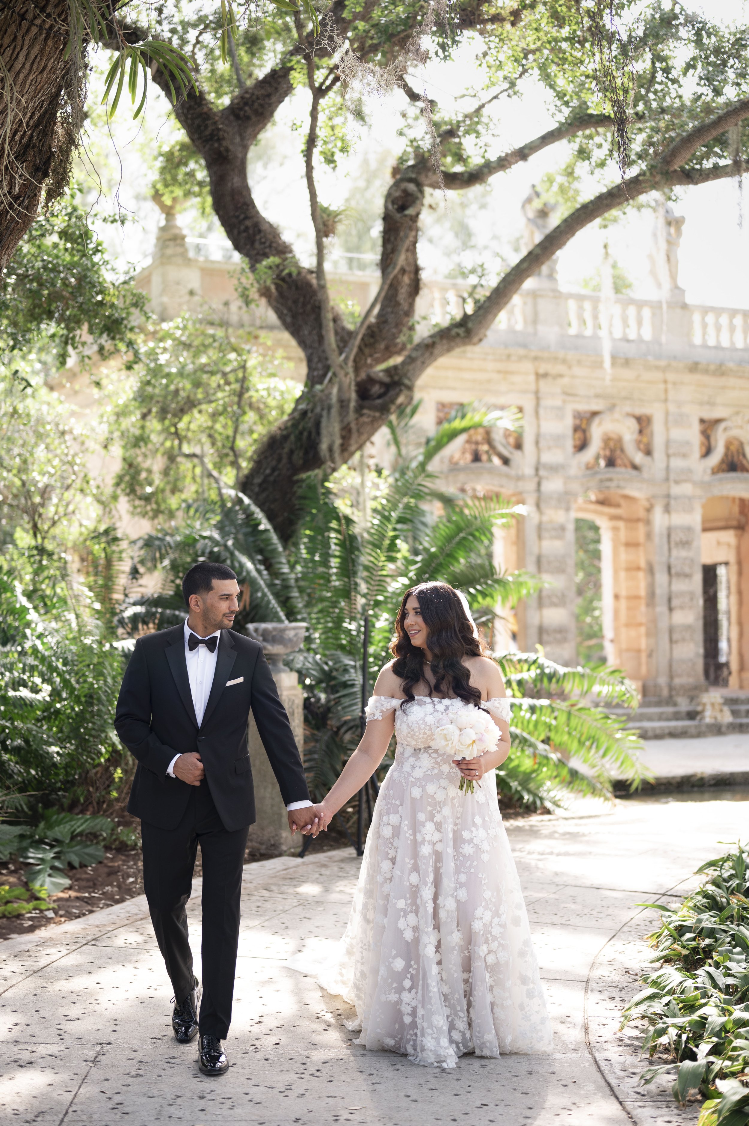 bride and groom walking and laughing through the gardens of Vizcaya museum