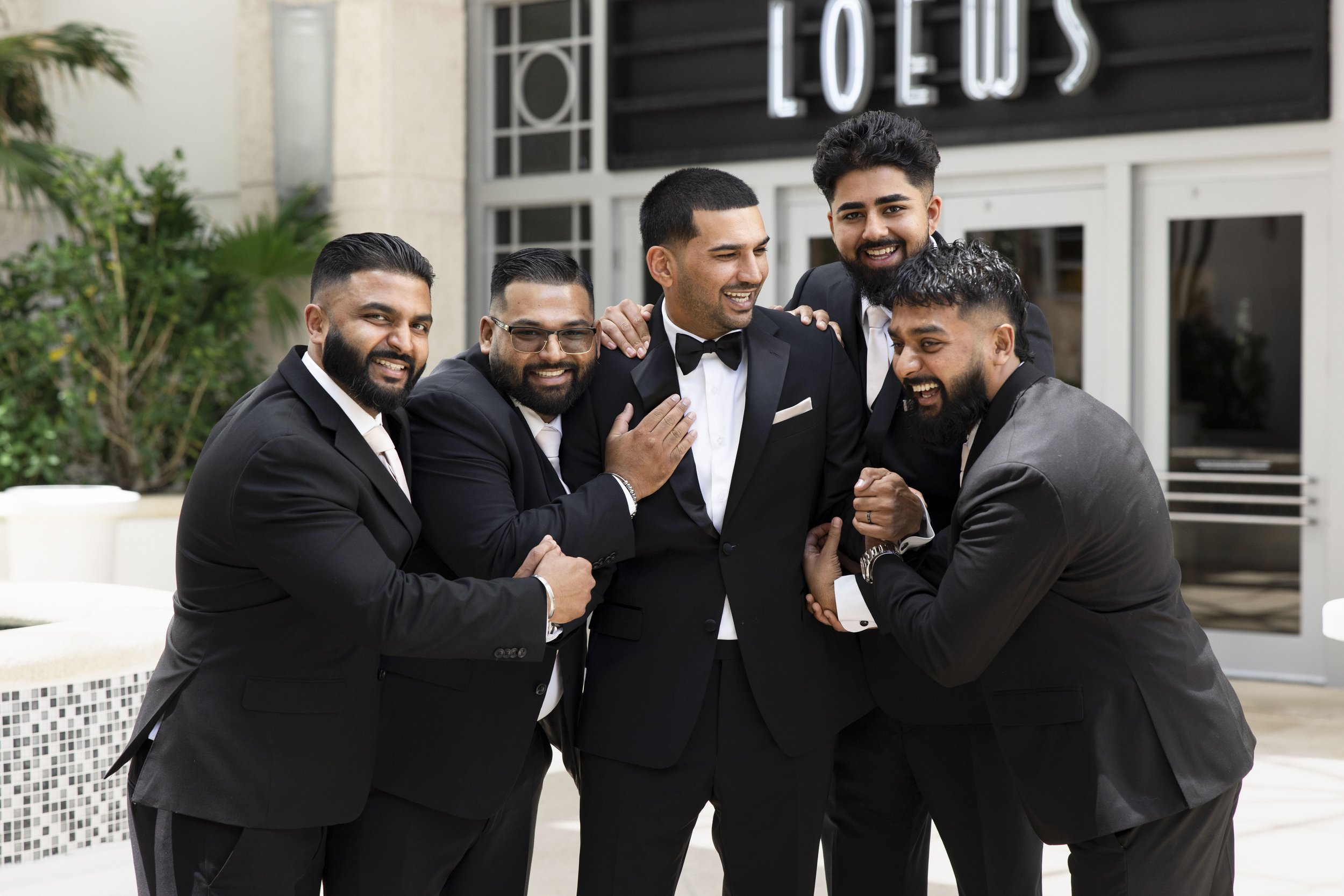 groom and groomsmen jocking in front of the Loews hotel miami beach