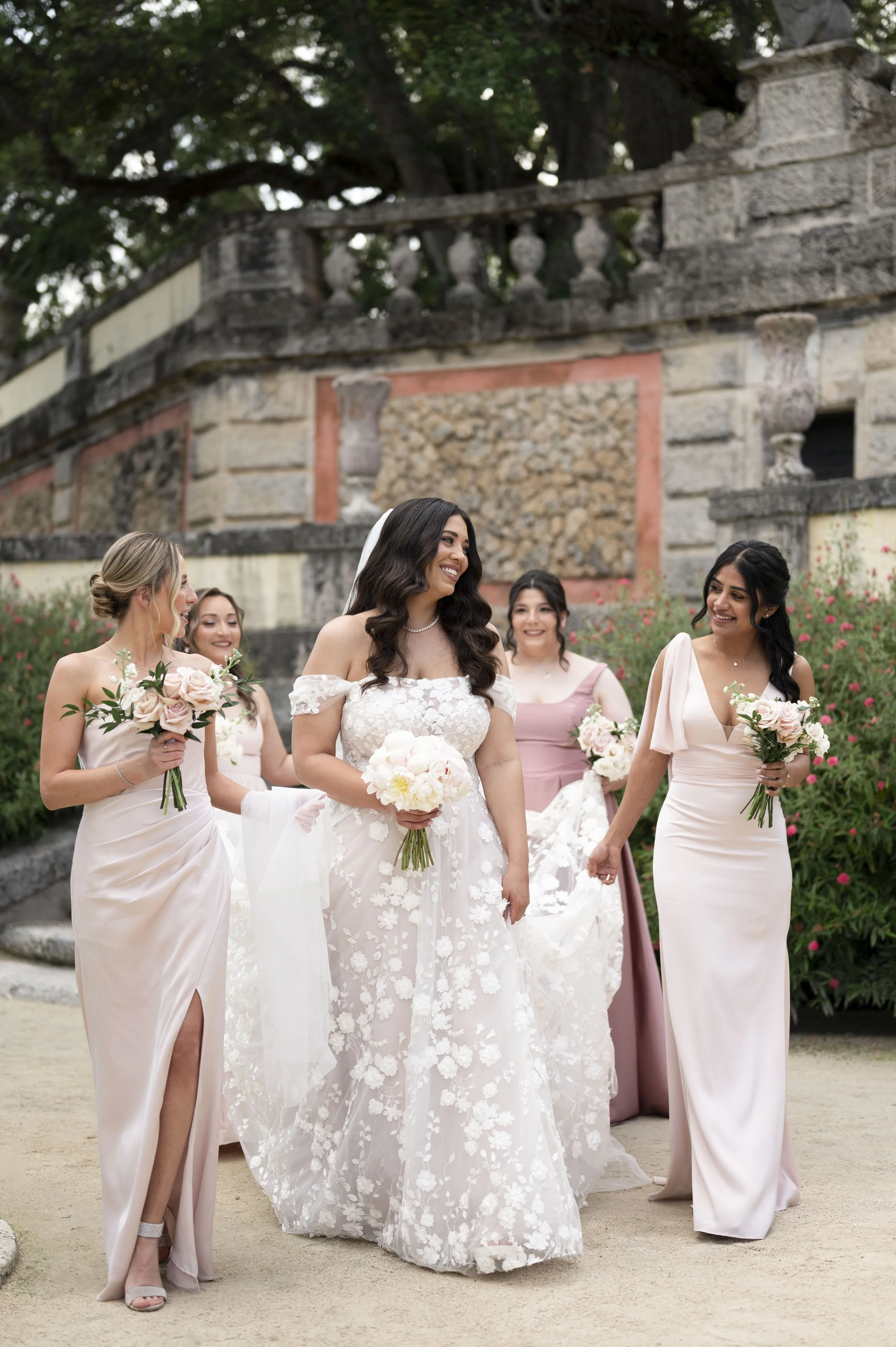 bride laughing with her bridesmaids in the Vizcaya museum and garderns.