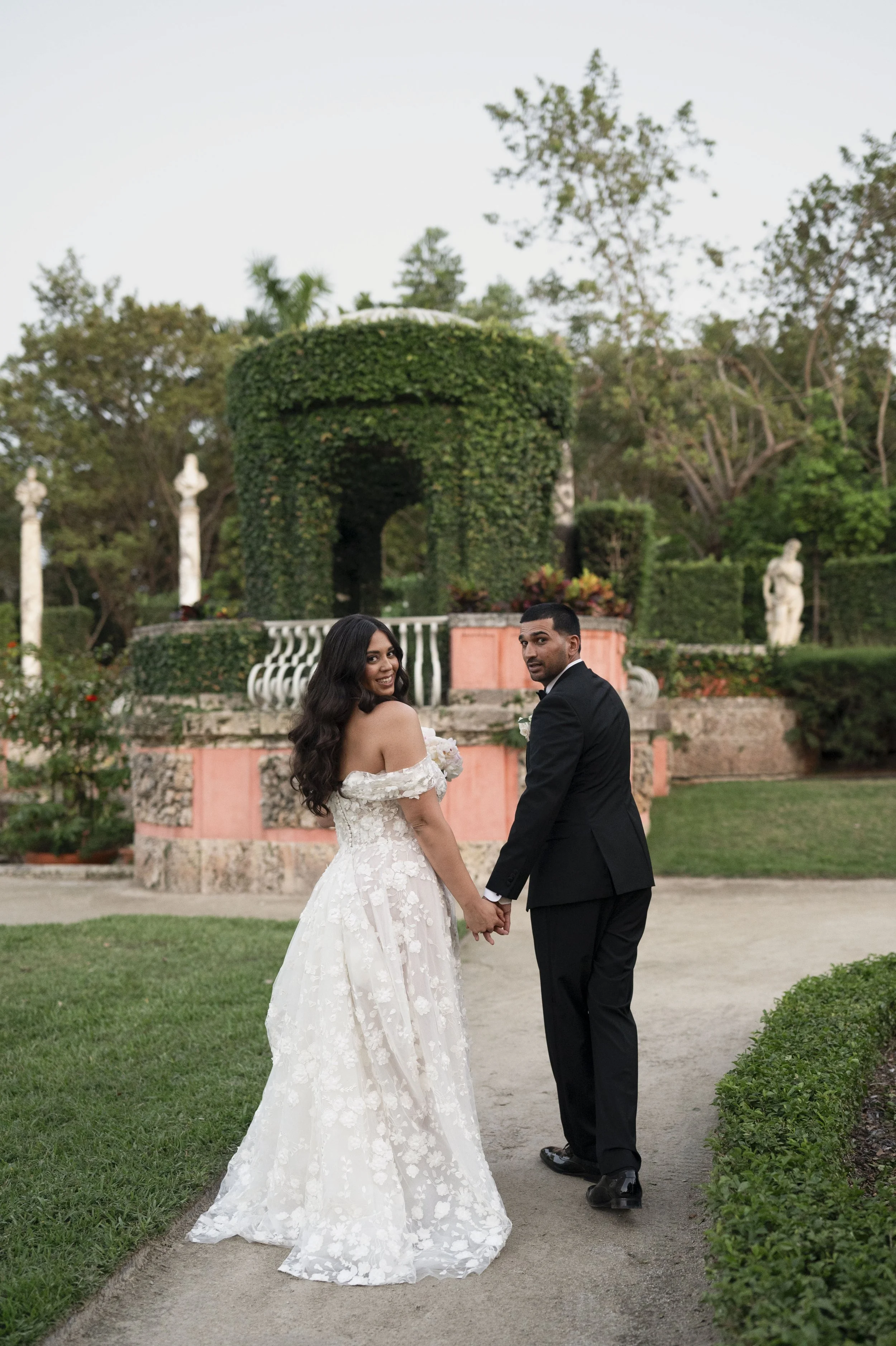 bride and groom walking through the gardens of vizcaya museum right after their ceremony in miami