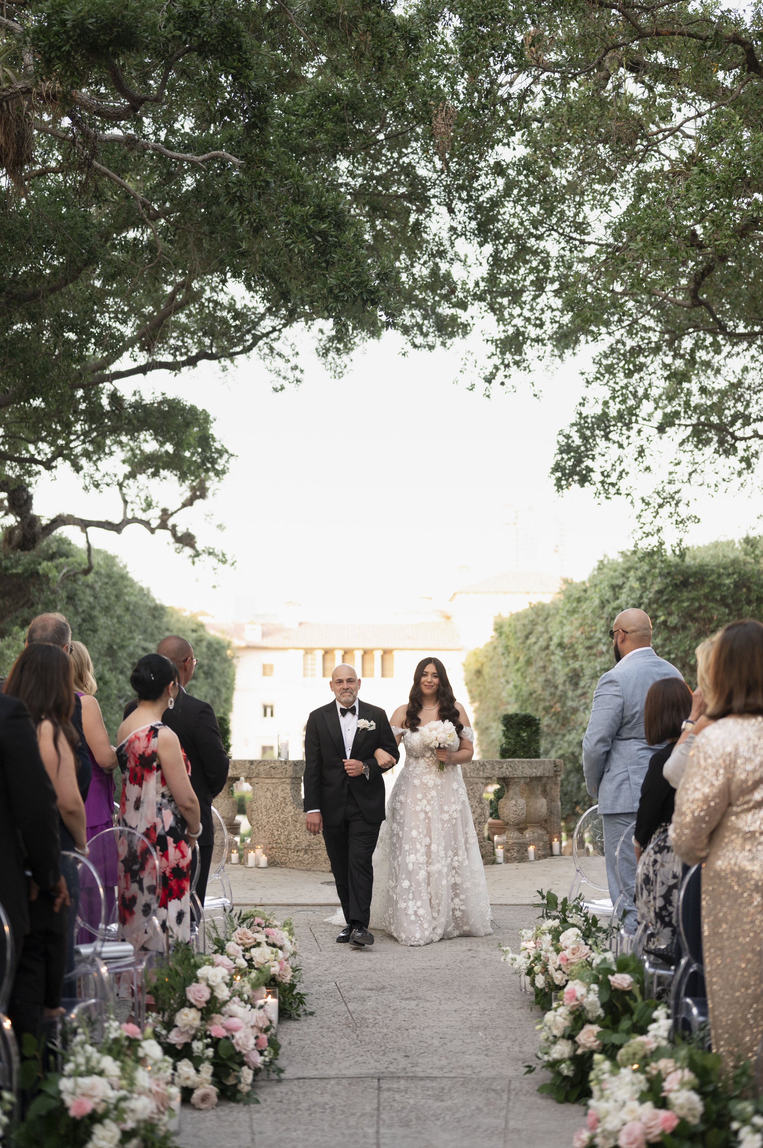 bride walks down the isle with her father in her wedding ceremony at the vizcaya museum in miami