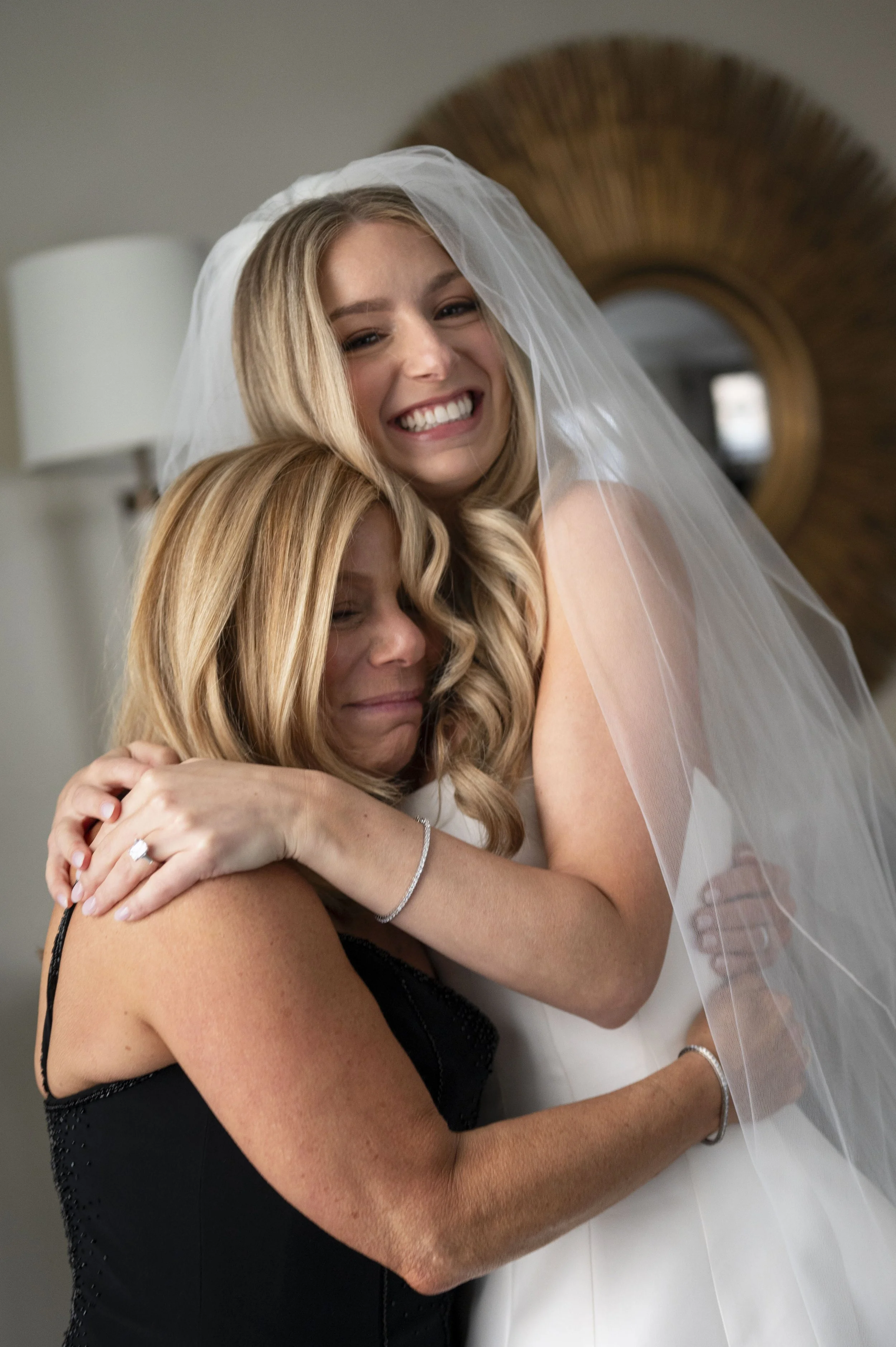 bride and mother hugging each other as bride gets ready for her wedding day