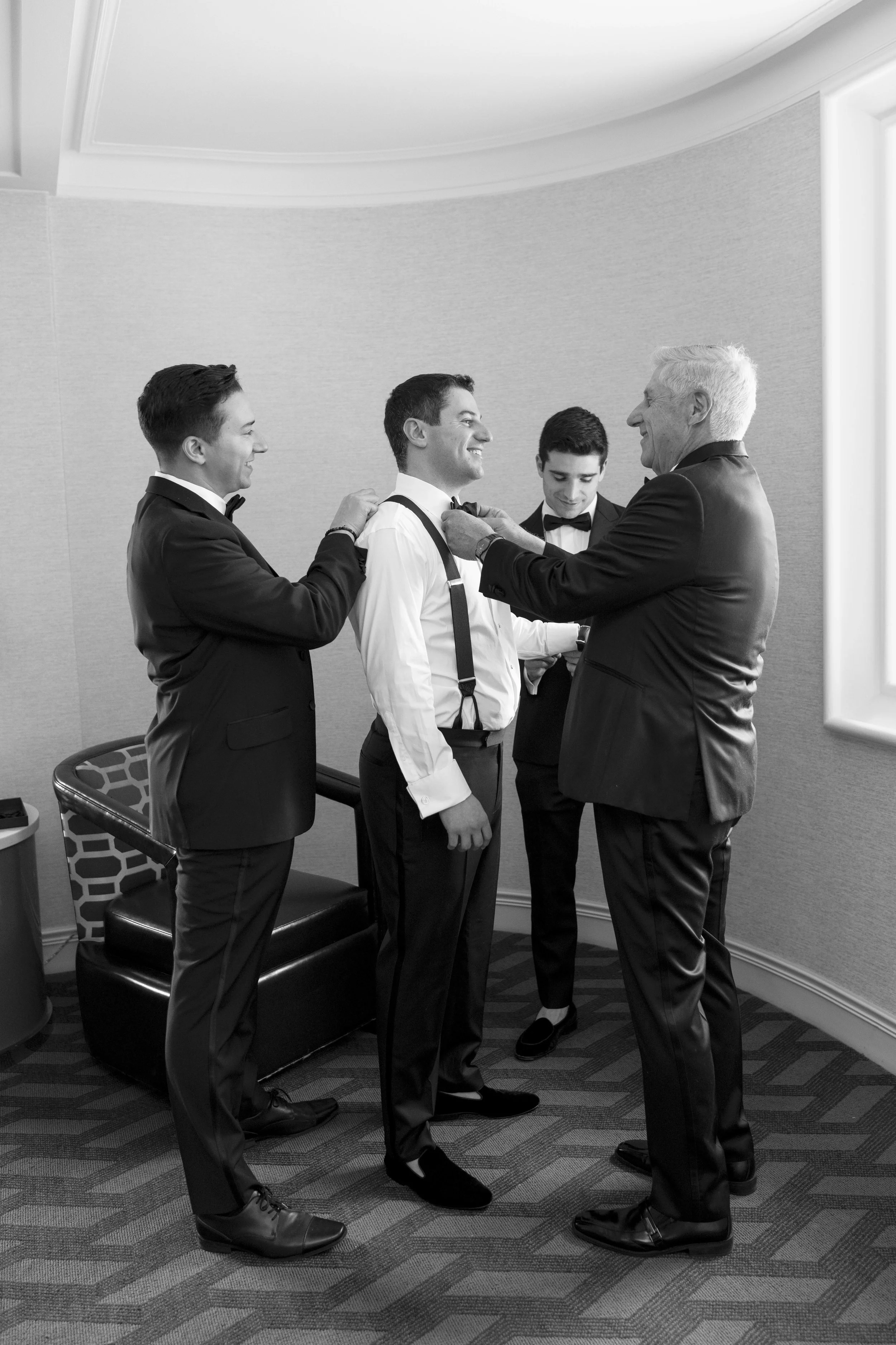 groom getting ready with his father and groomsmen in his suite