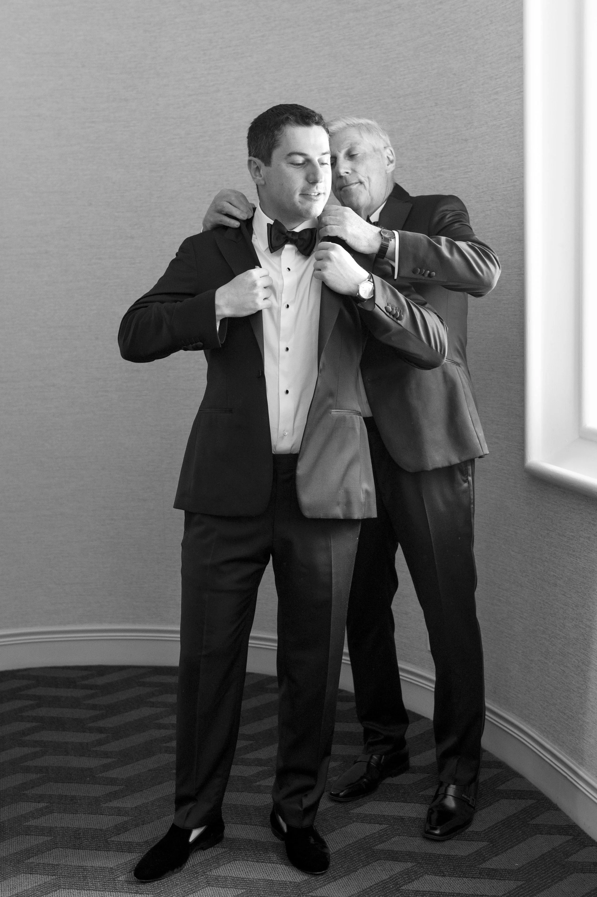 father helps groom put his jacket on his wedding day