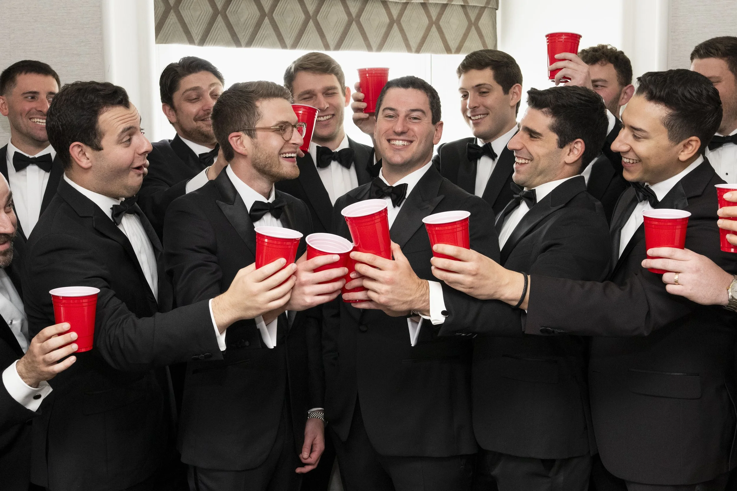 grop photo of groom ad groomsmen holding solo red cups as they toast to the wedding day
