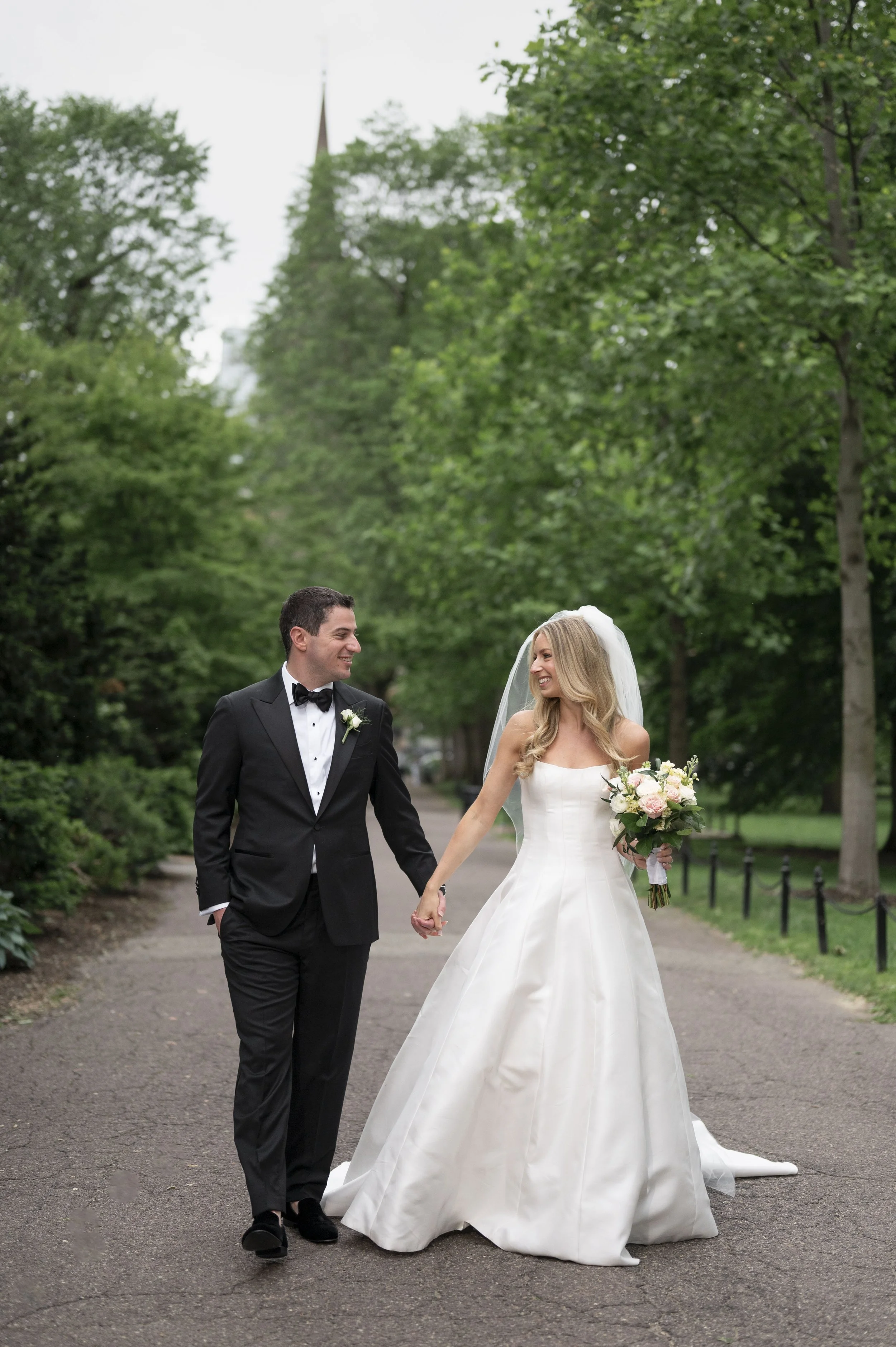 bride and groom walking holdings hands at the boston public library