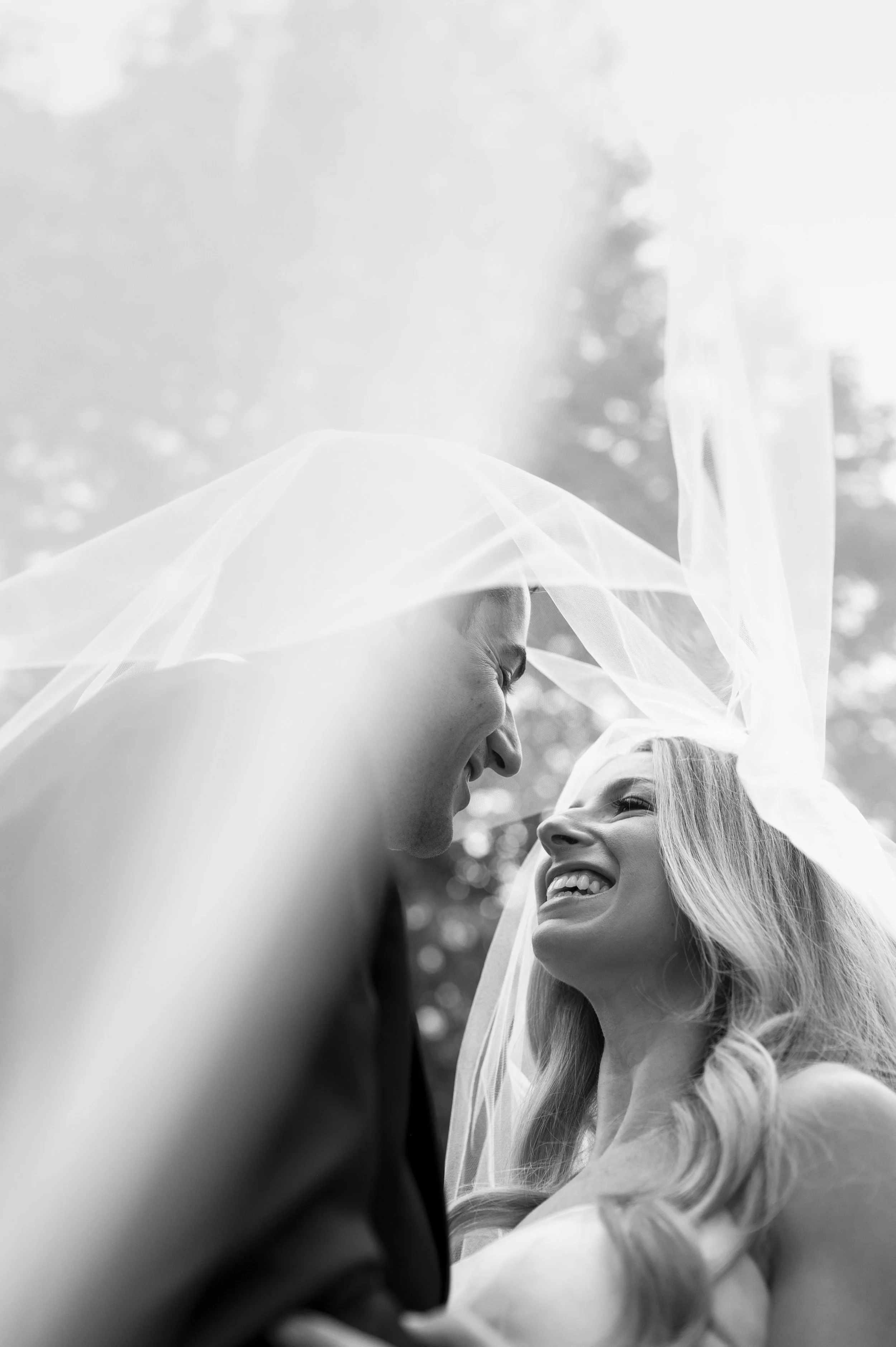 bride and groom under the veil as they look at eachother