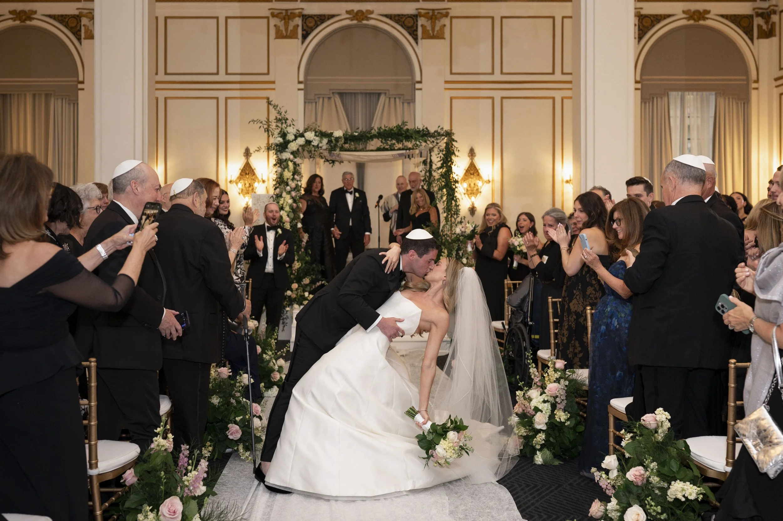 groom deeps bride for a kiss in the middle of the isle of their jewish ceremony at the park plaza hotel boston