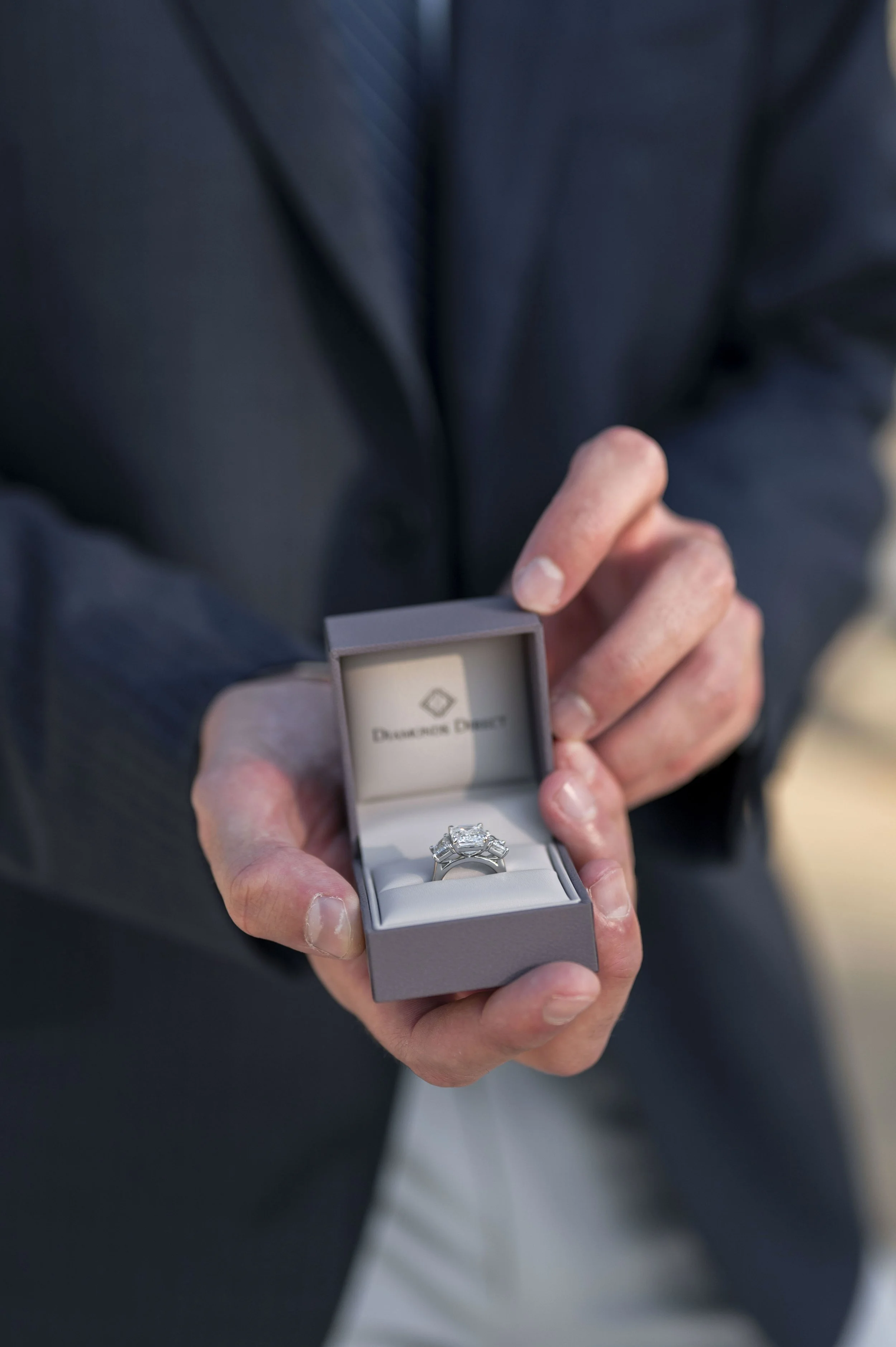 detail of an engagement ring box and the hands of a man holding it (Copy)